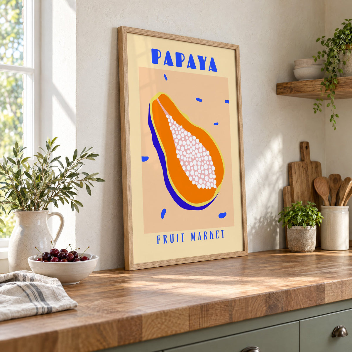 Papaya Fruit Market print in an oak frame leaning on a butcher block island beside a bowl of cherries