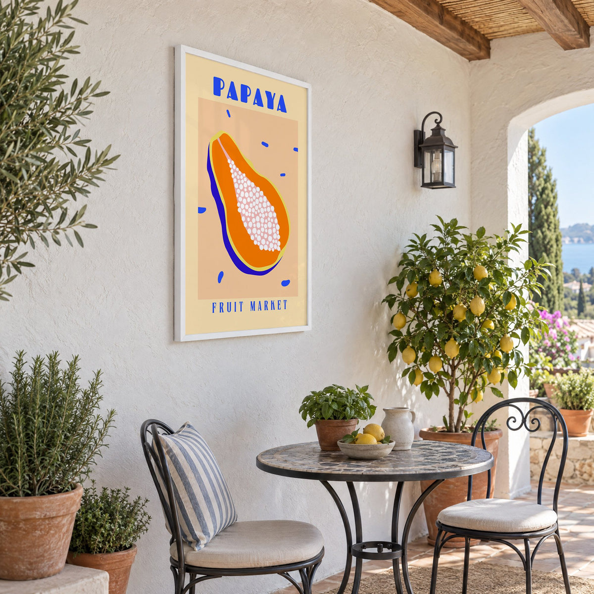 Papaya Fruit Market print in a white frame on a sunny patio wall beside a potted lemon tree