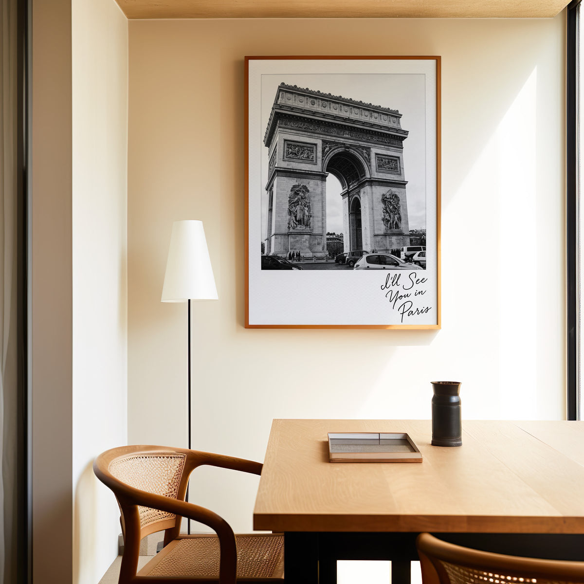 Arc de Triomphe instant photo with Paris script print in an oak frame above a dining table and cane chair