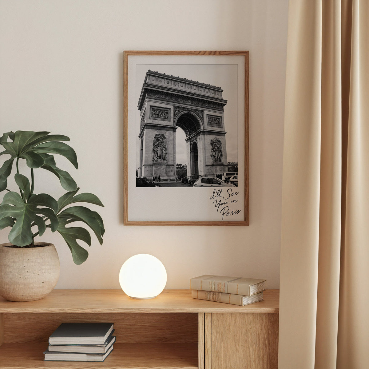 Arc de Triomphe instant photo with Paris script print in a walnut frame above an oak cabinet with a glowing globe lamp