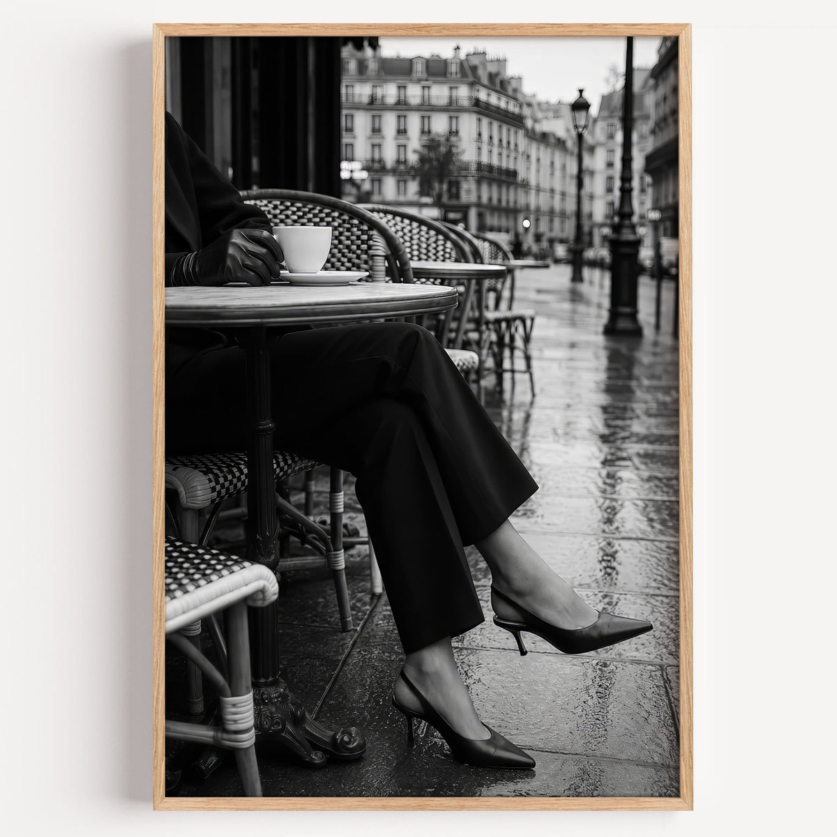 Black heels at rainy Paris café table print in a light oak frame on a plain white wall