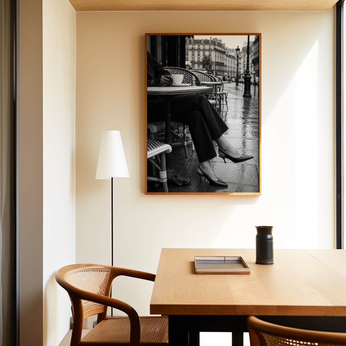 Black heels at rainy Paris café table print in an oak frame above a dining table and cane chair