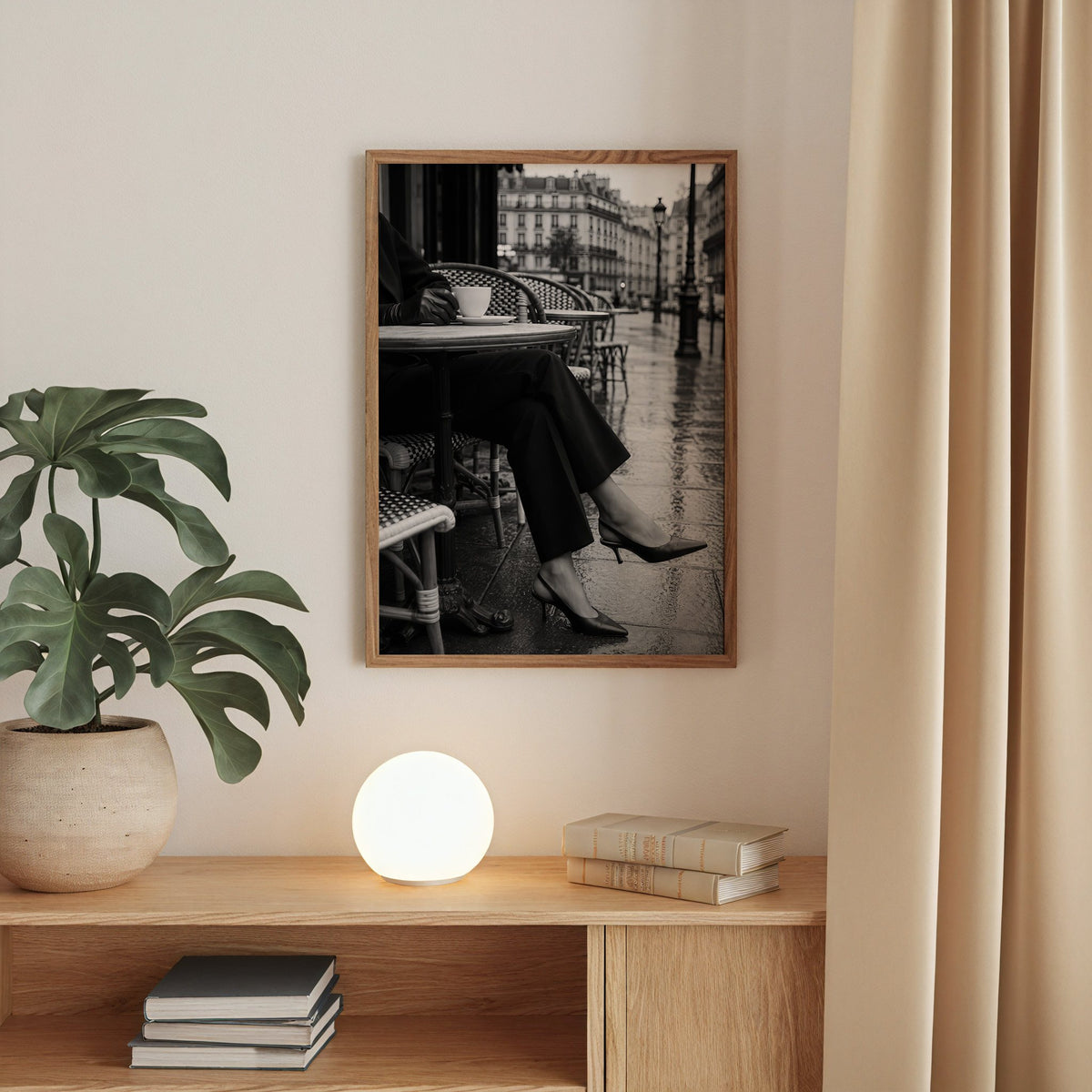 Black heels at rainy Paris café table print in a walnut frame above an oak cabinet with a glowing globe lamp