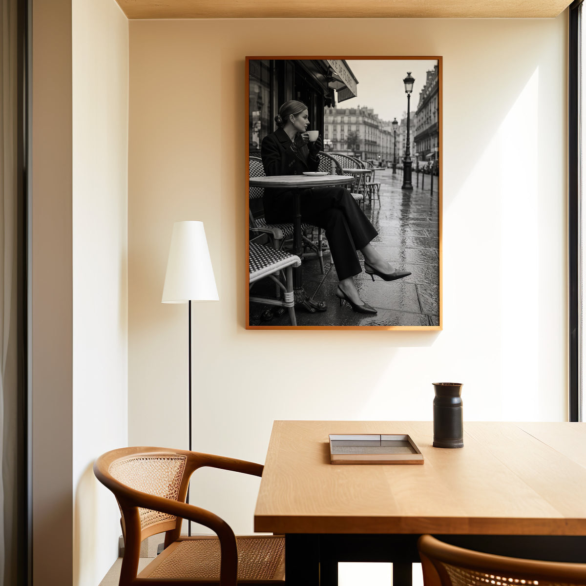 Black and white Paris cafe woman with coffee print in an oak frame above a dining table and cane chair