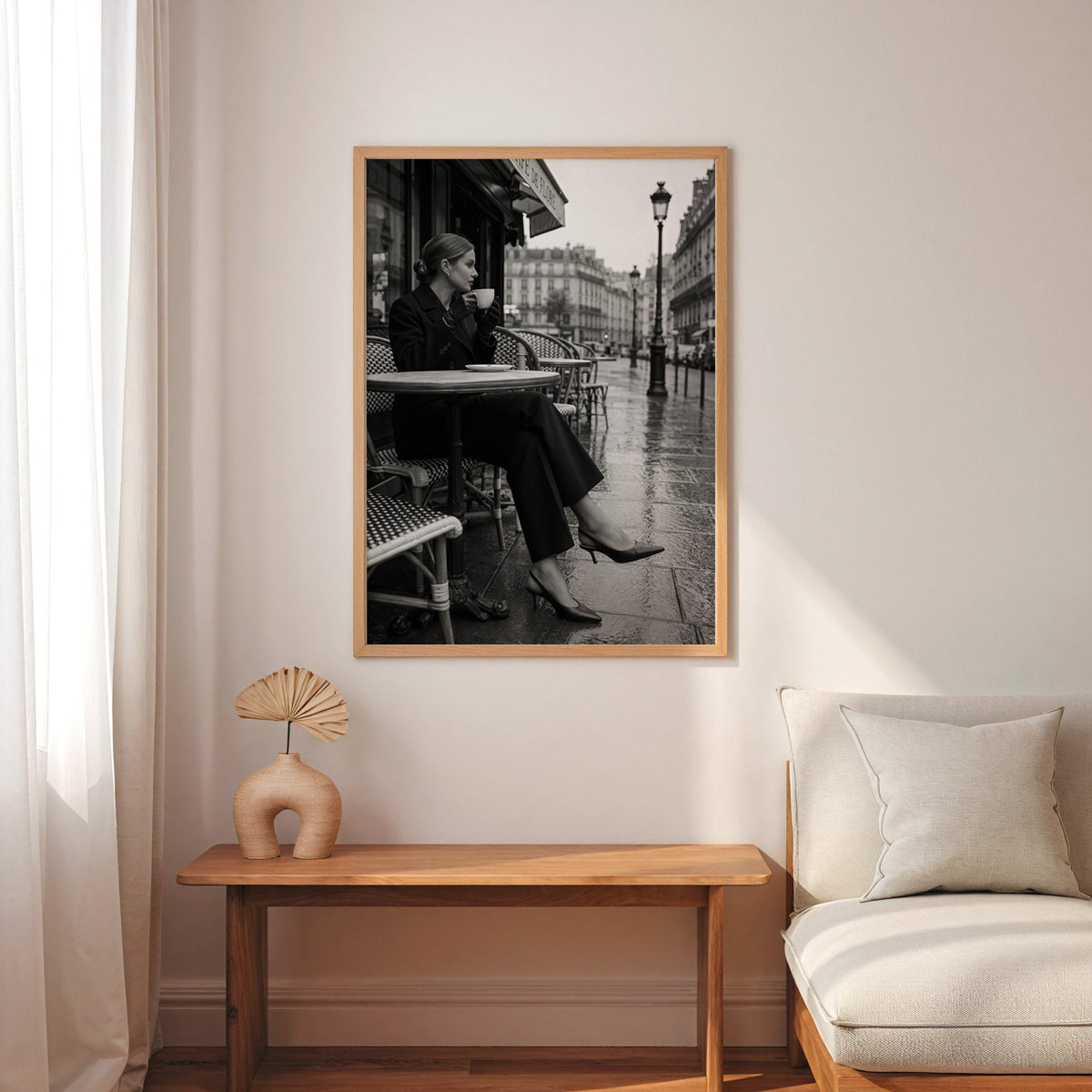 Black and white Paris cafe woman with coffee print in an oak frame above a narrow console with an arched vase