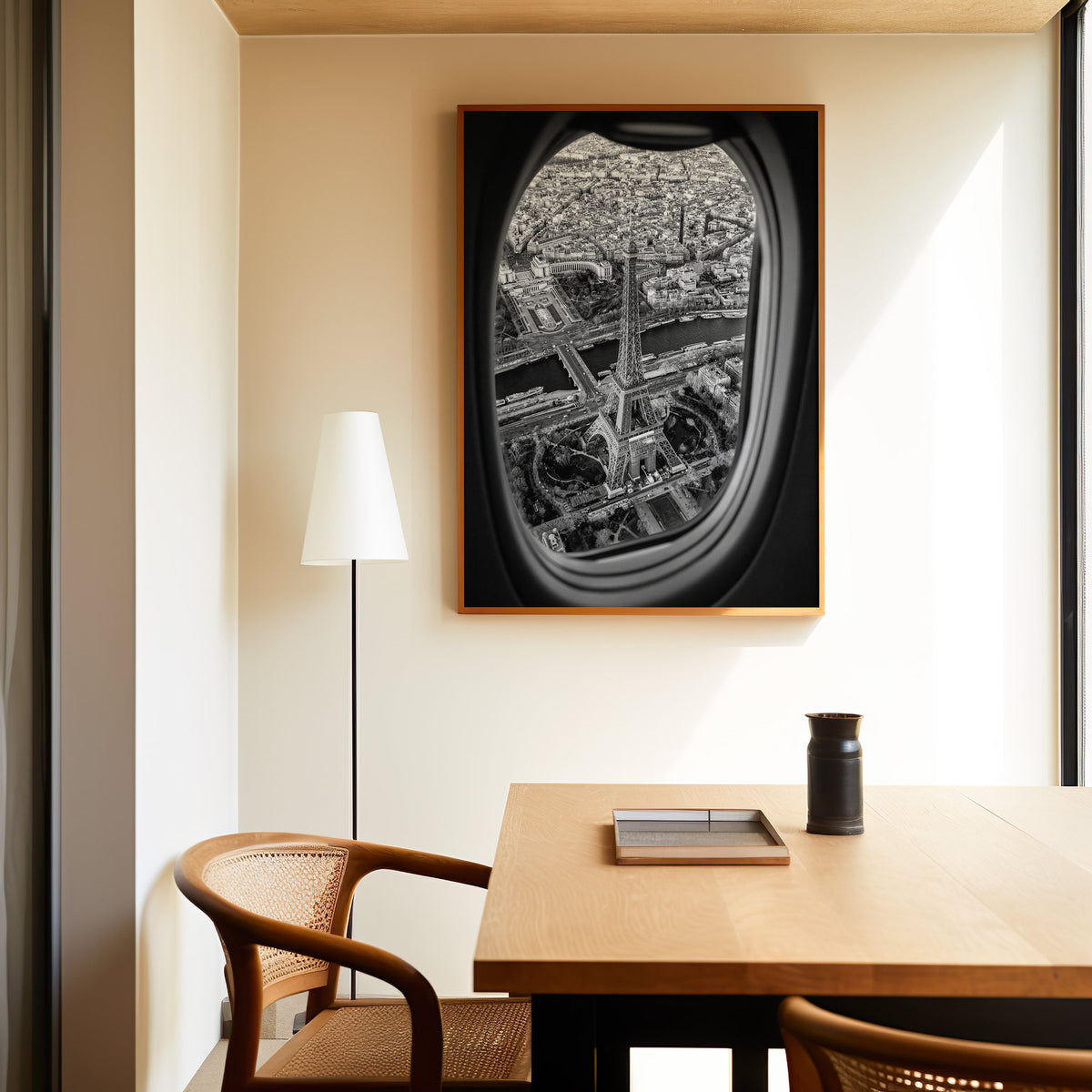 Eiffel Tower seen through an airplane window print in an oak frame above a dining table and cane chair