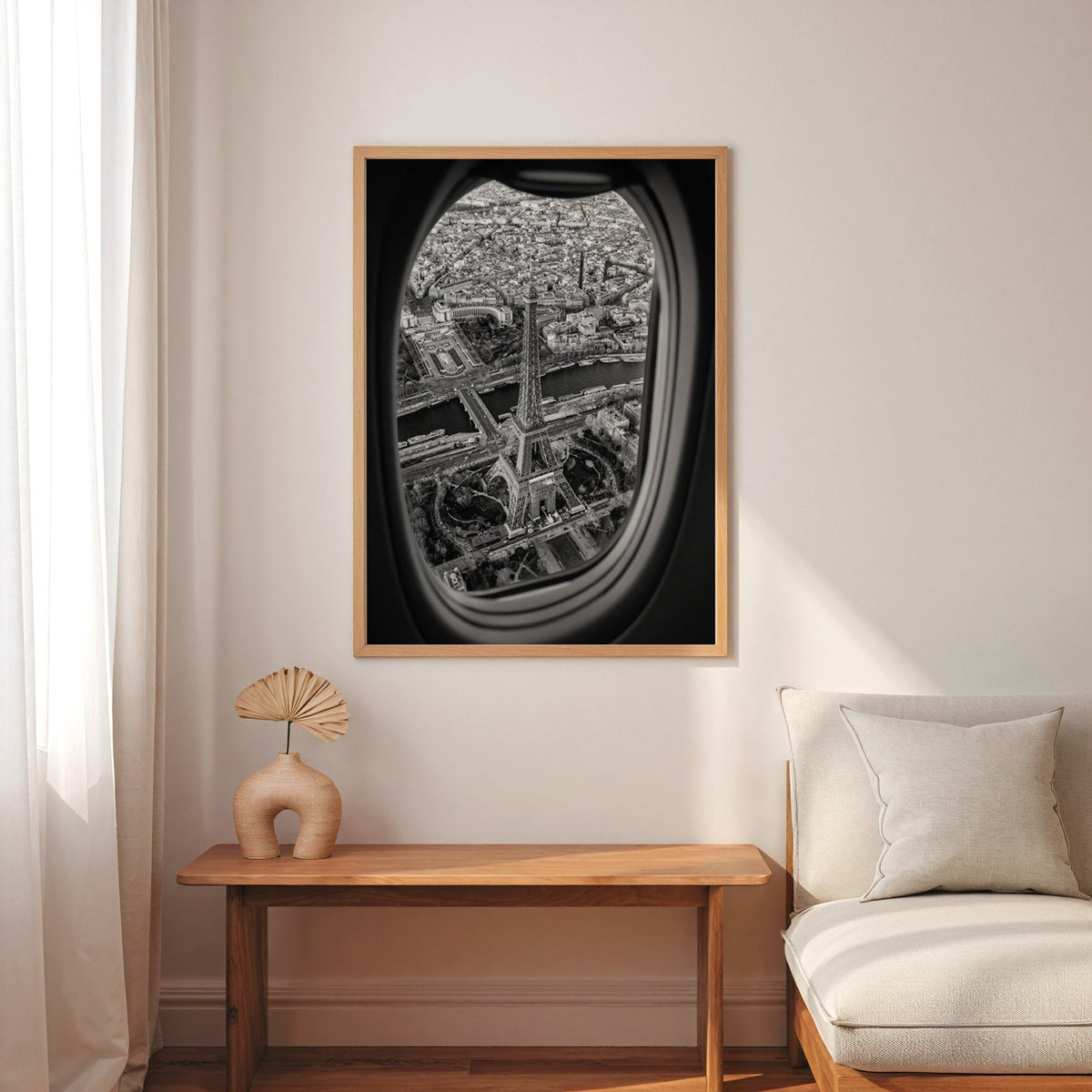 Eiffel Tower seen through an airplane window print in an oak frame above a narrow console with an arched vase