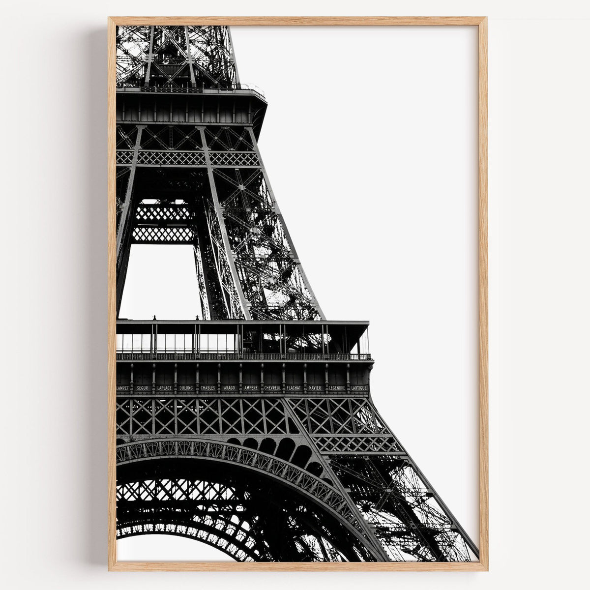 Eiffel Tower close-up on white background print in a light oak frame on a plain white wall