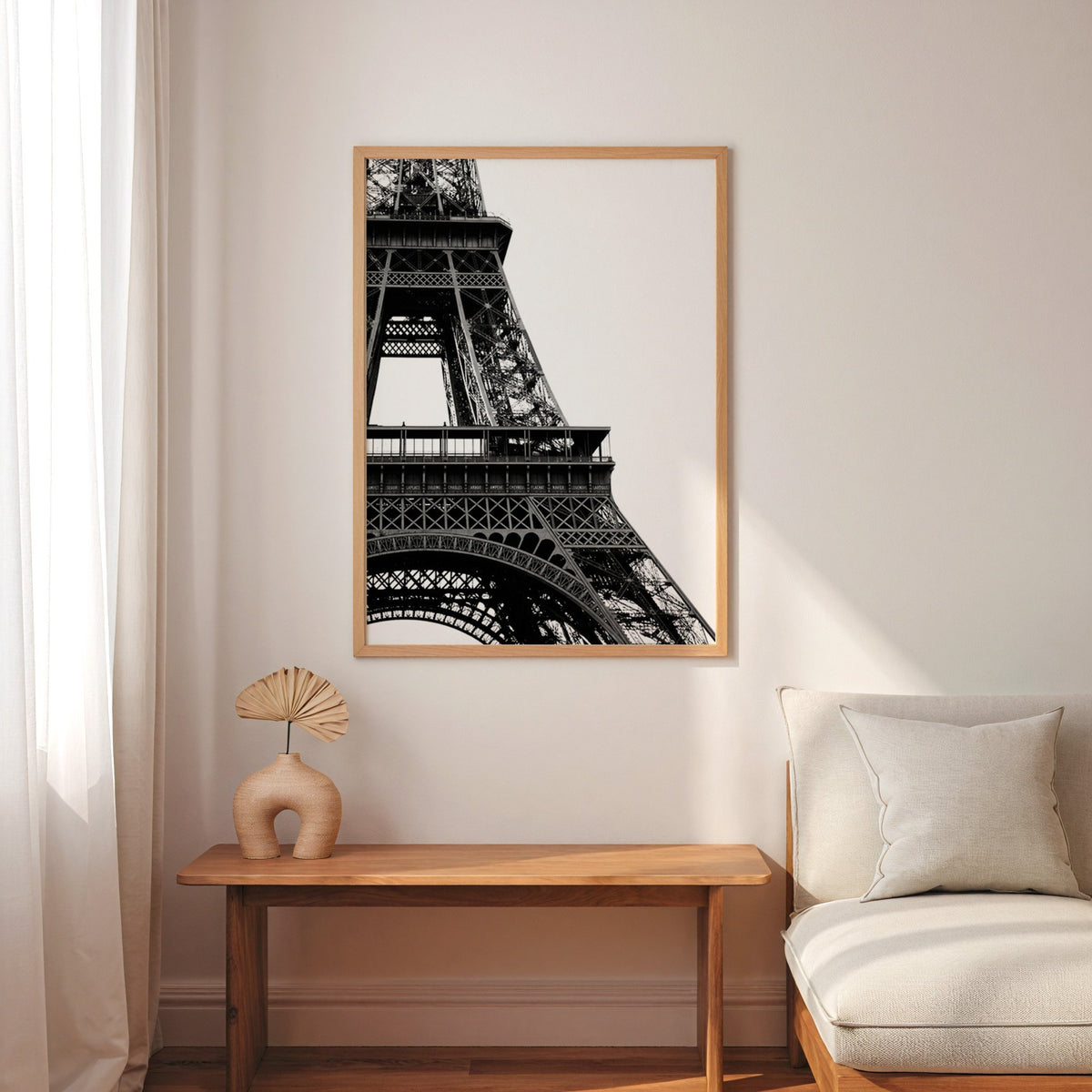 Eiffel Tower close-up on white background print in an oak frame above a narrow console with an arched vase