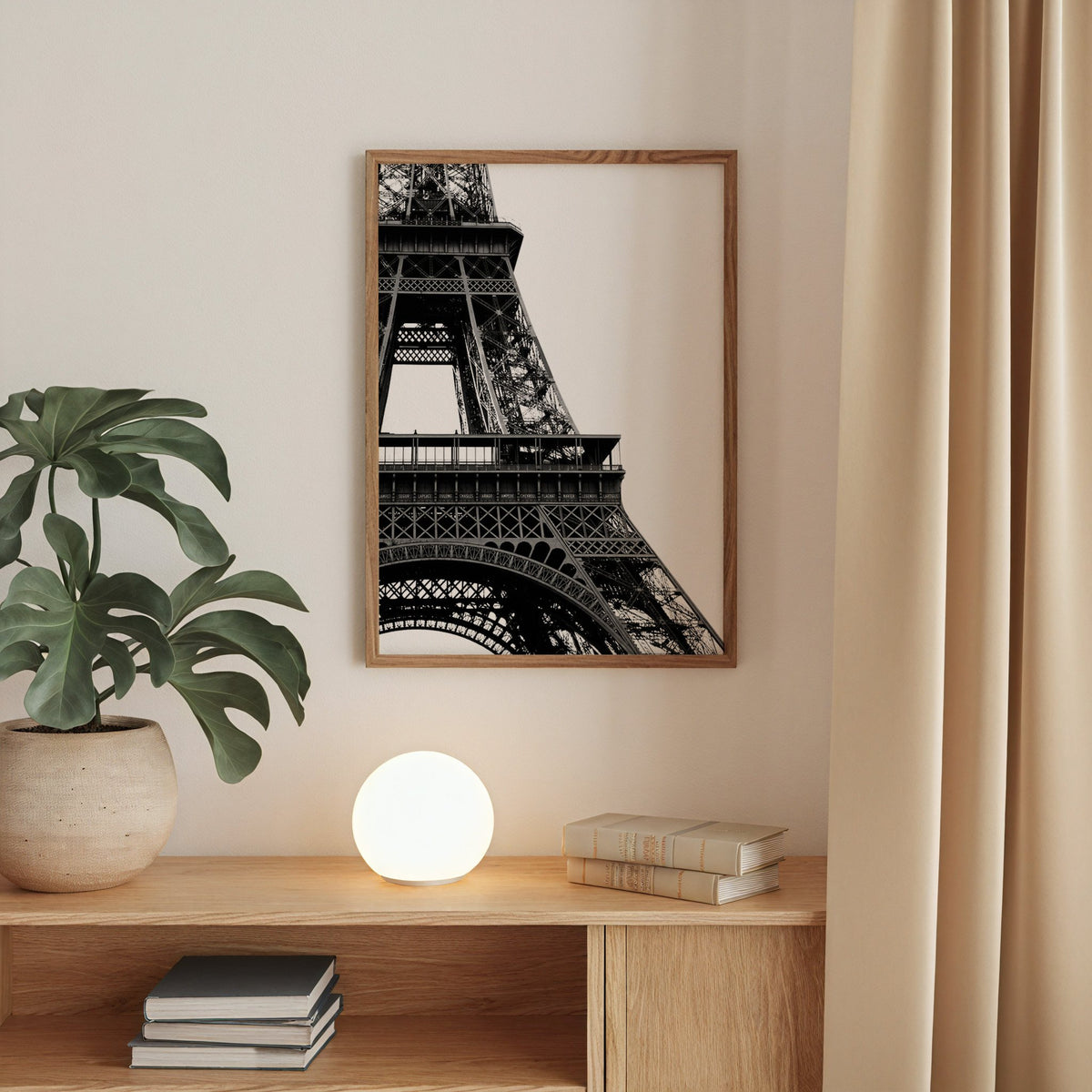 Eiffel Tower close-up on white background print in a walnut frame above an oak cabinet with a glowing globe lamp