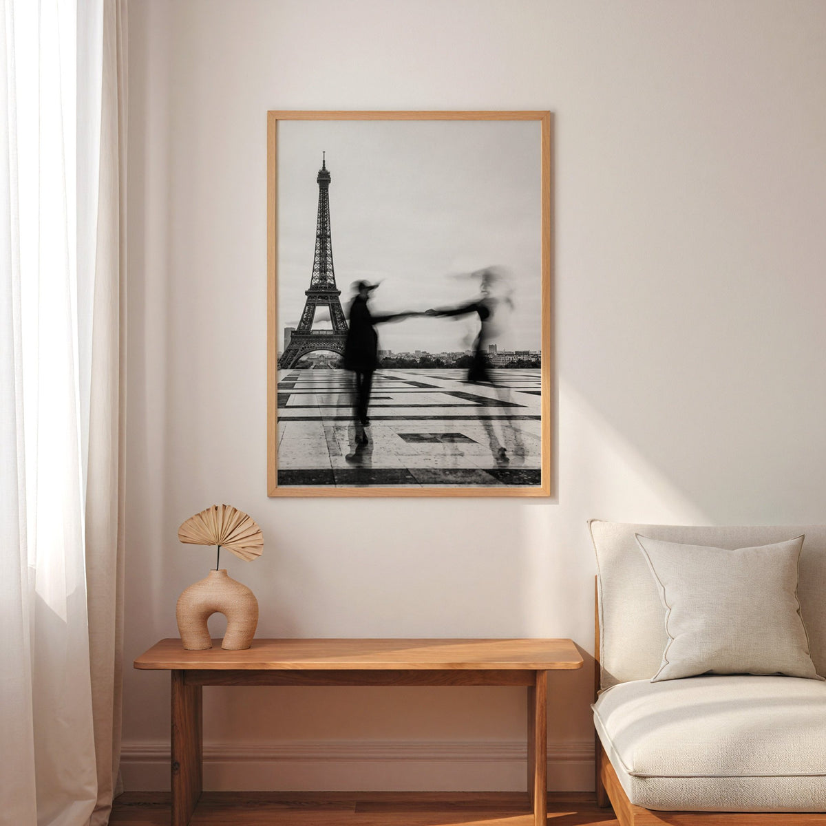 Blurred couple twirling near the Eiffel Tower print in an oak frame above a narrow console with an arched vase