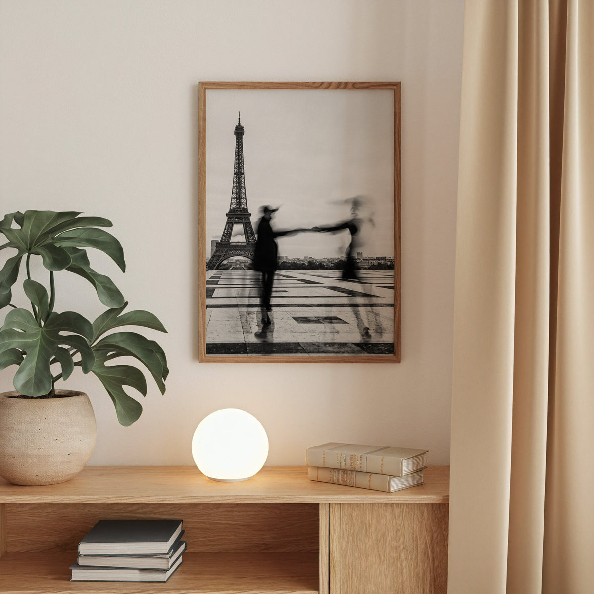 Blurred couple twirling near the Eiffel Tower print in a walnut frame above an oak cabinet with a glowing globe lamp