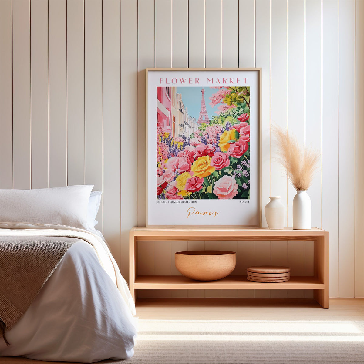 Paris flower market print in an oak frame on a wood bench against a white shiplap bedroom wall with pampas grass