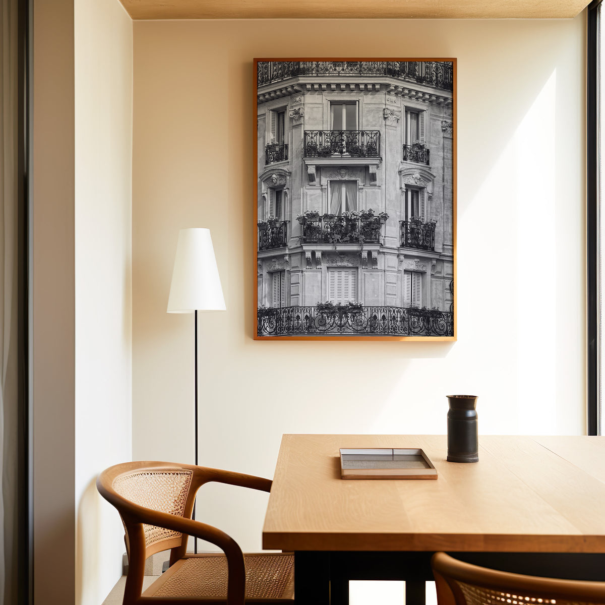 Paris facade with wrought iron balconies print in an oak frame above a dining table and cane chair