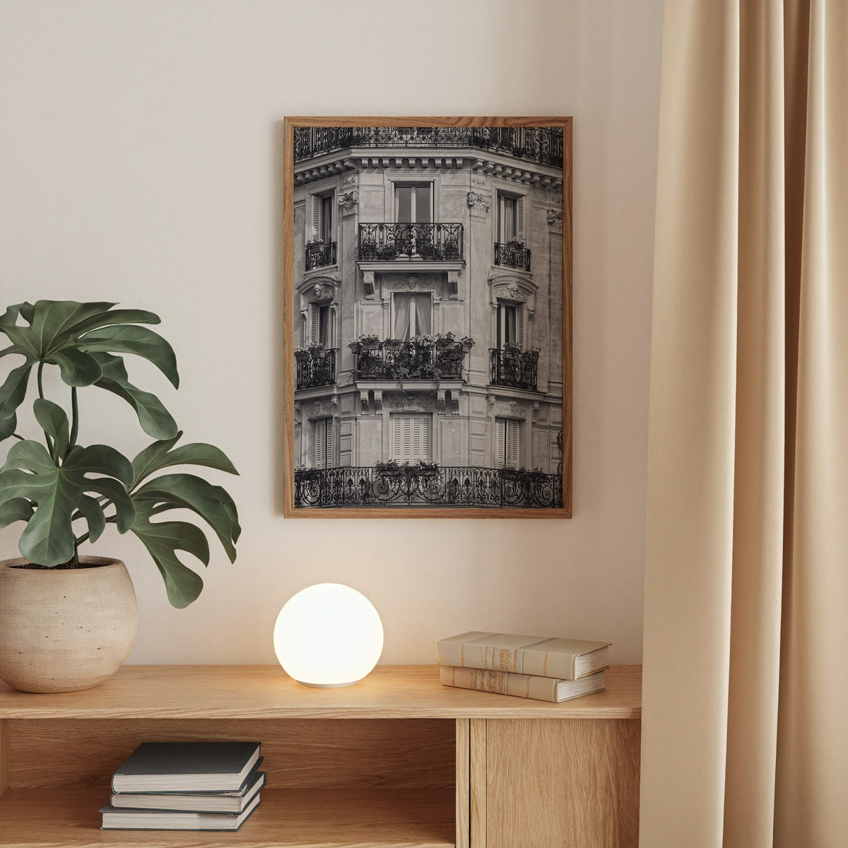 Paris facade with wrought iron balconies print in a walnut frame above an oak cabinet with a glowing globe lamp