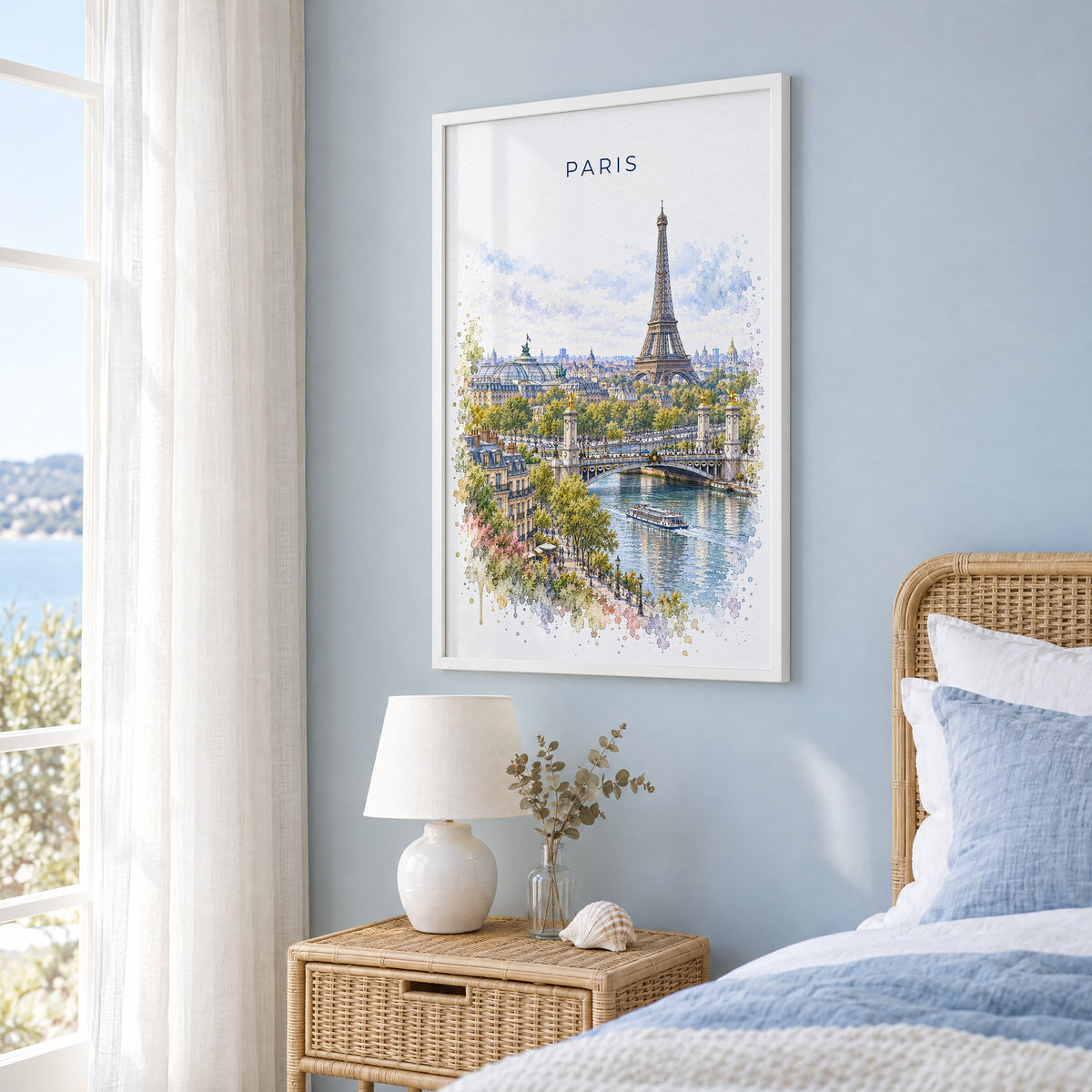 Paris watercolor print in a white frame on a pale blue wall beside a rattan bed in a coastal bedroom