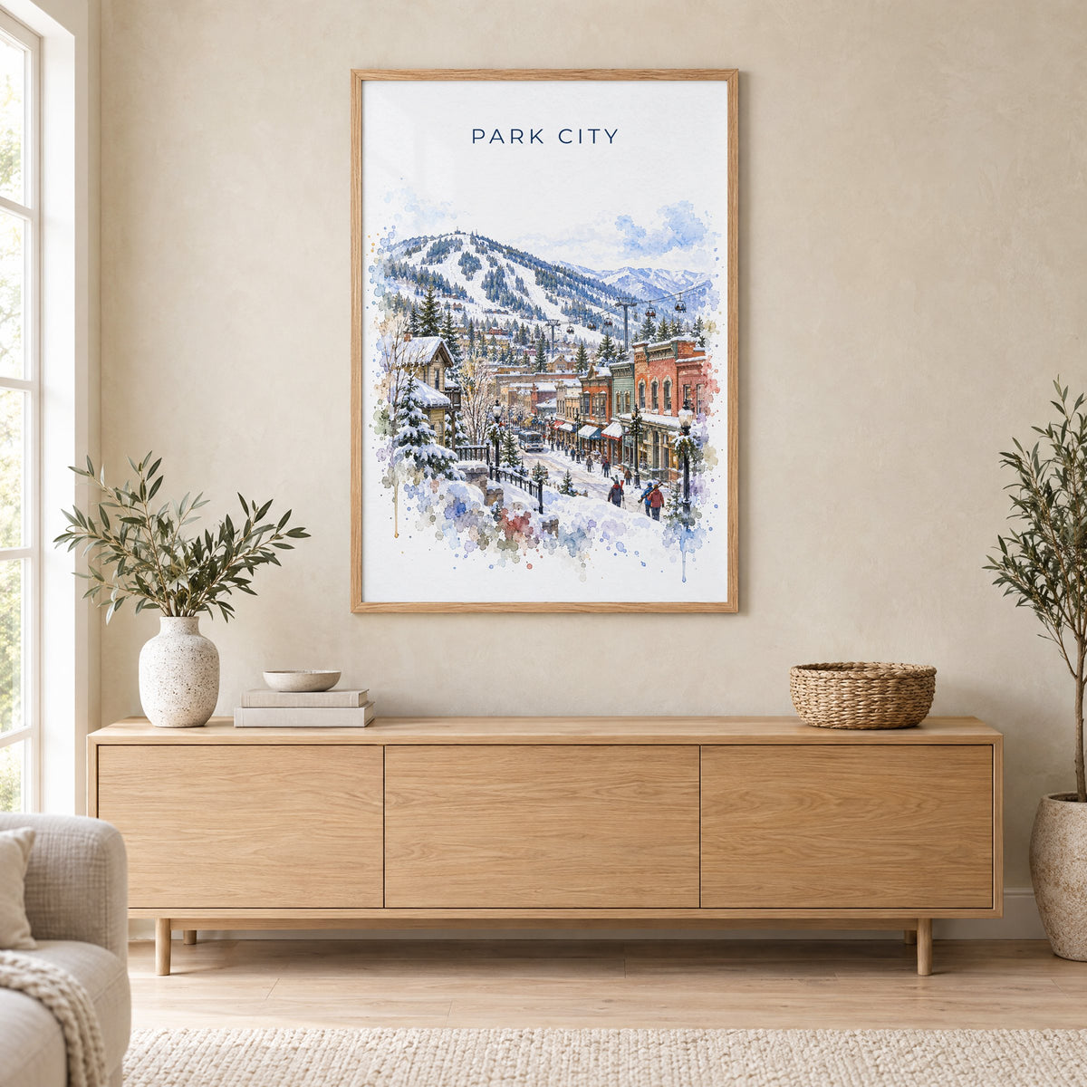 Park City watercolor print in an oak frame above a light wood sideboard in a Scandinavian living room