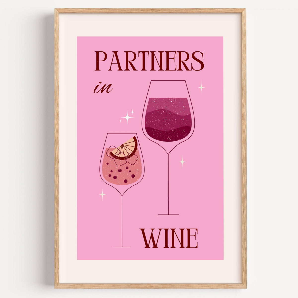 Partners in Wine two glasses pink print in a light oak frame on a plain white wall