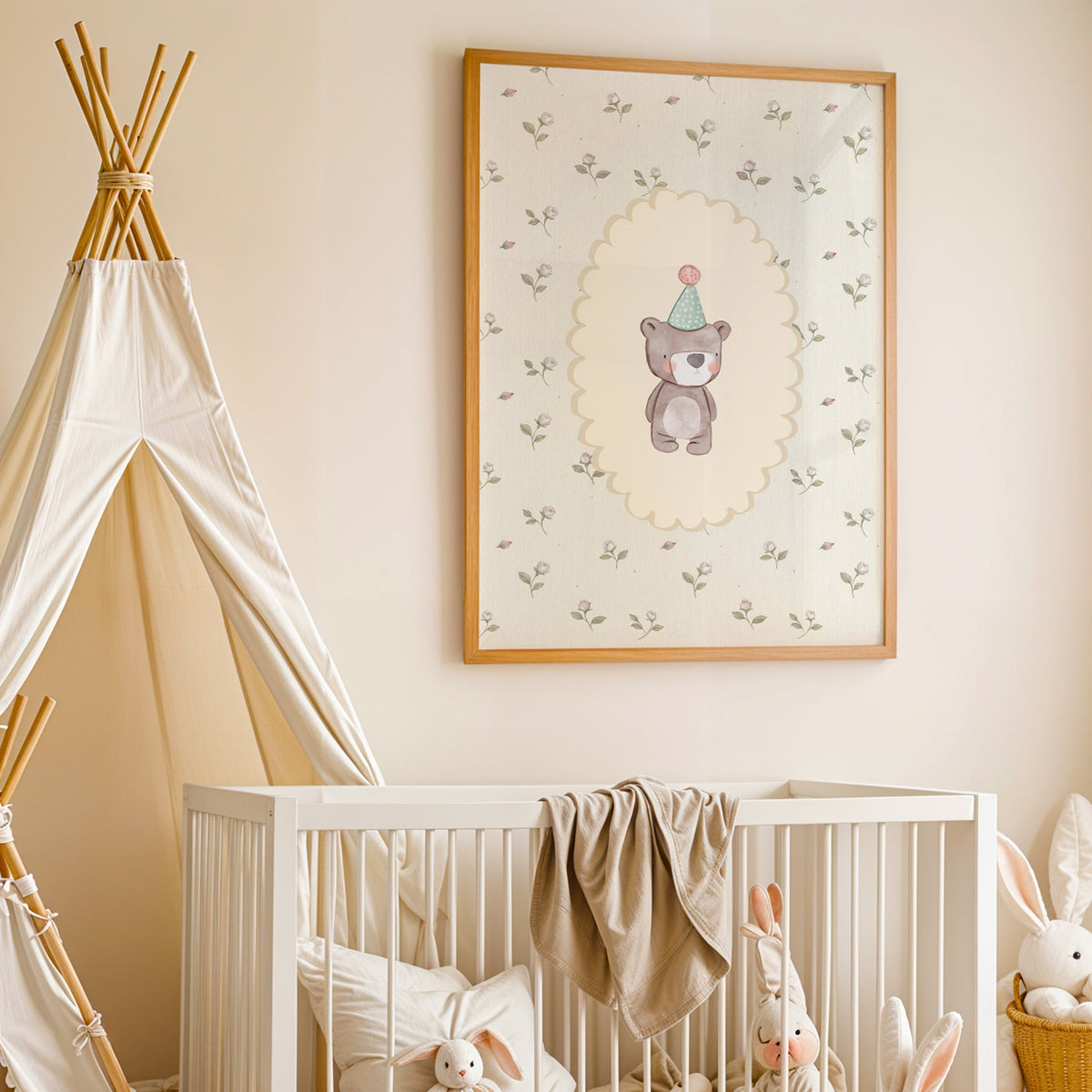 Bear in a mint party hat on rosebud wallpaper nursery print in an oak frame above a white crib beside a canvas teepee
