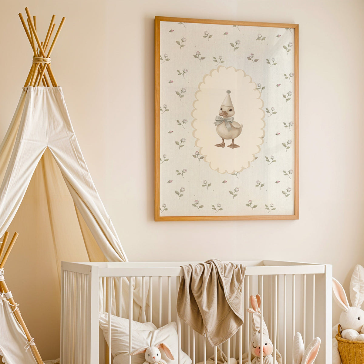 Party duckling in cream oval on rosebuds nursery print in an oak frame above a white crib beside a canvas teepee