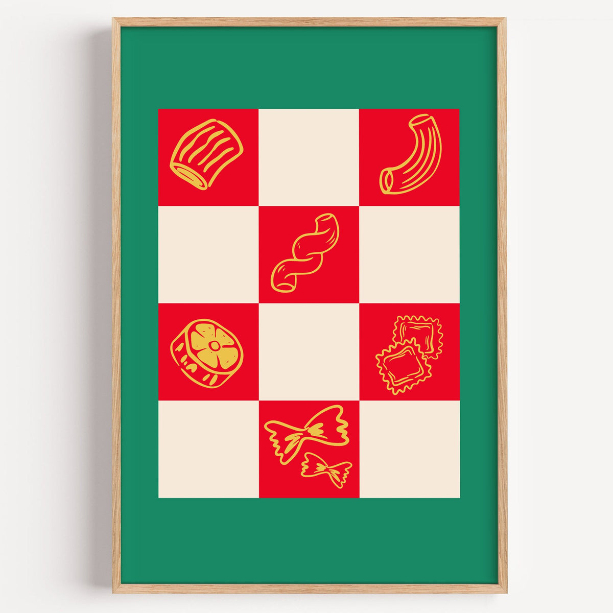 Red checkerboard pasta shapes print with green border in a light oak frame on a plain white wall