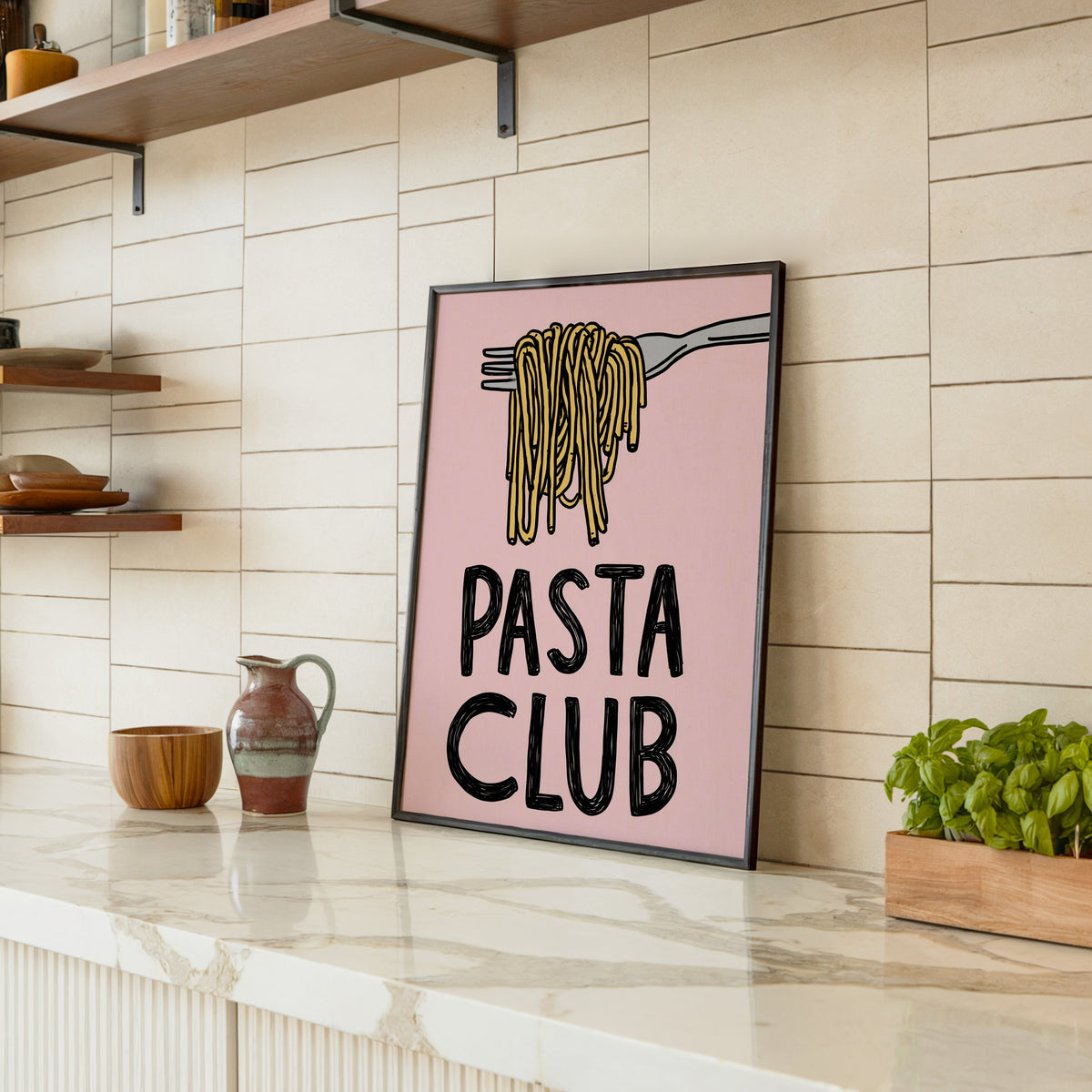 Pasta Club print in a black frame leaning on a marble counter in a tiled kitchen