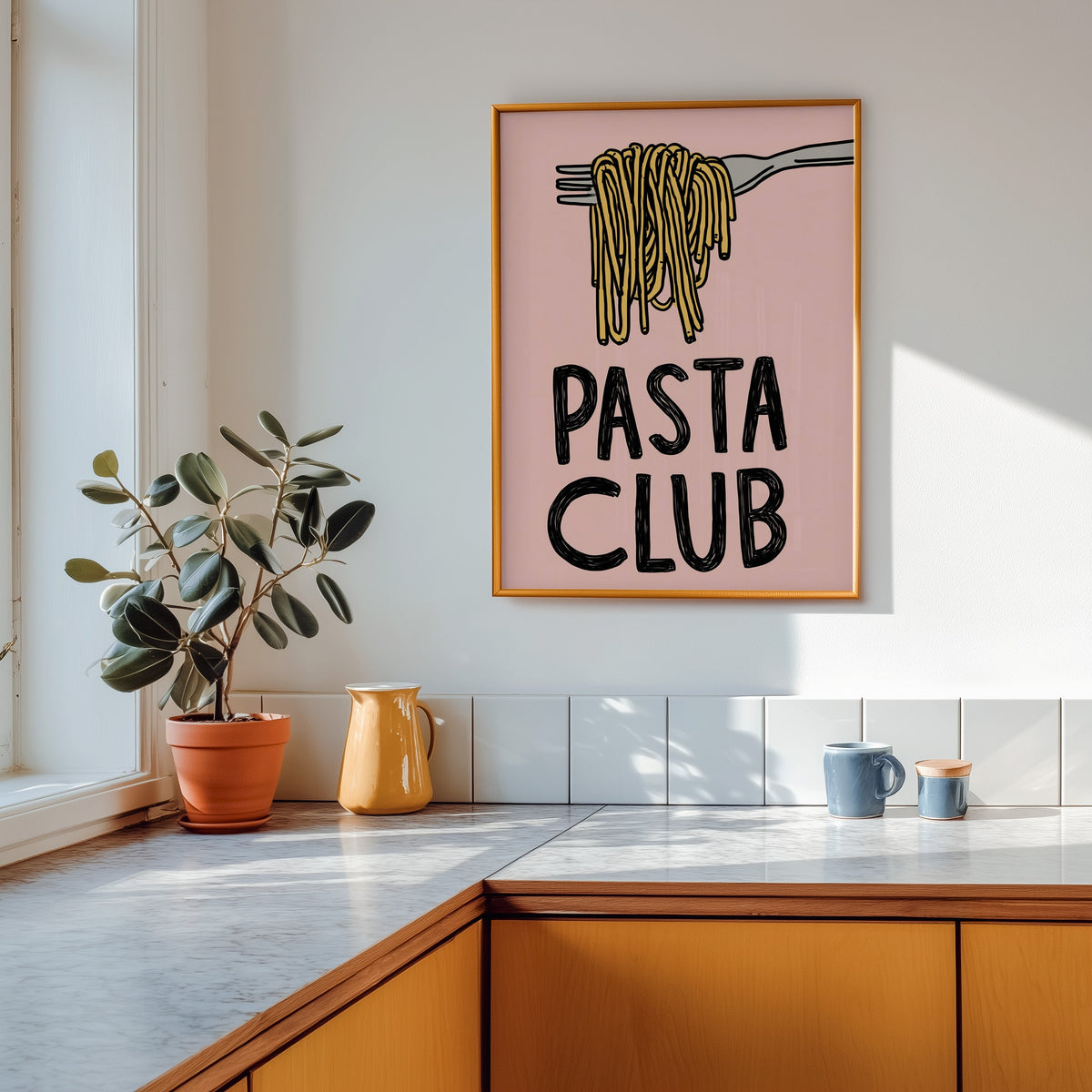 Pasta Club print shown in a gold frame above a marble counter in a tan kitchen