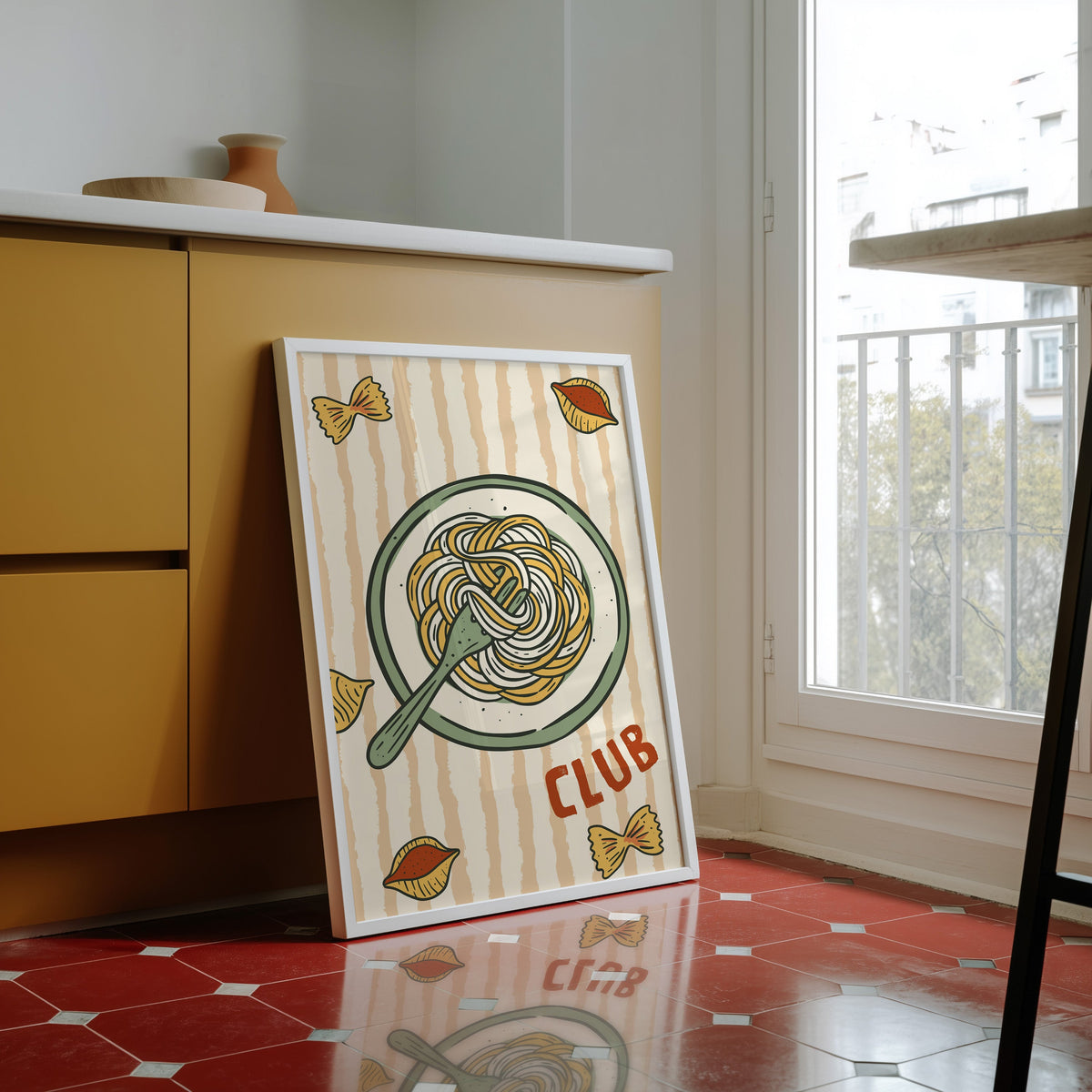 Pasta Club print in a white frame against yellow cabinets on a red tiled floor