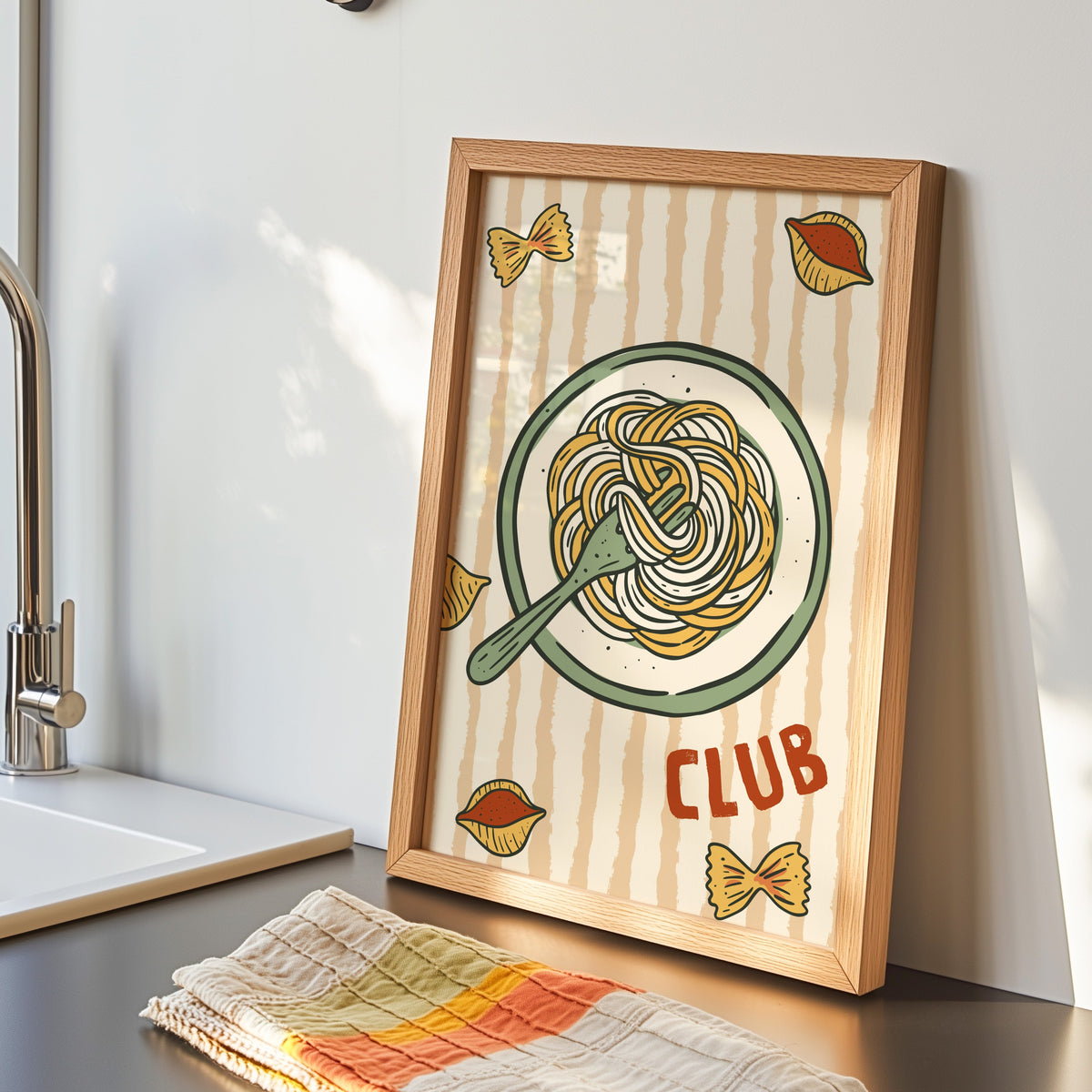 Pasta Club print in an oak frame by the kitchen sink beside a striped tea towel