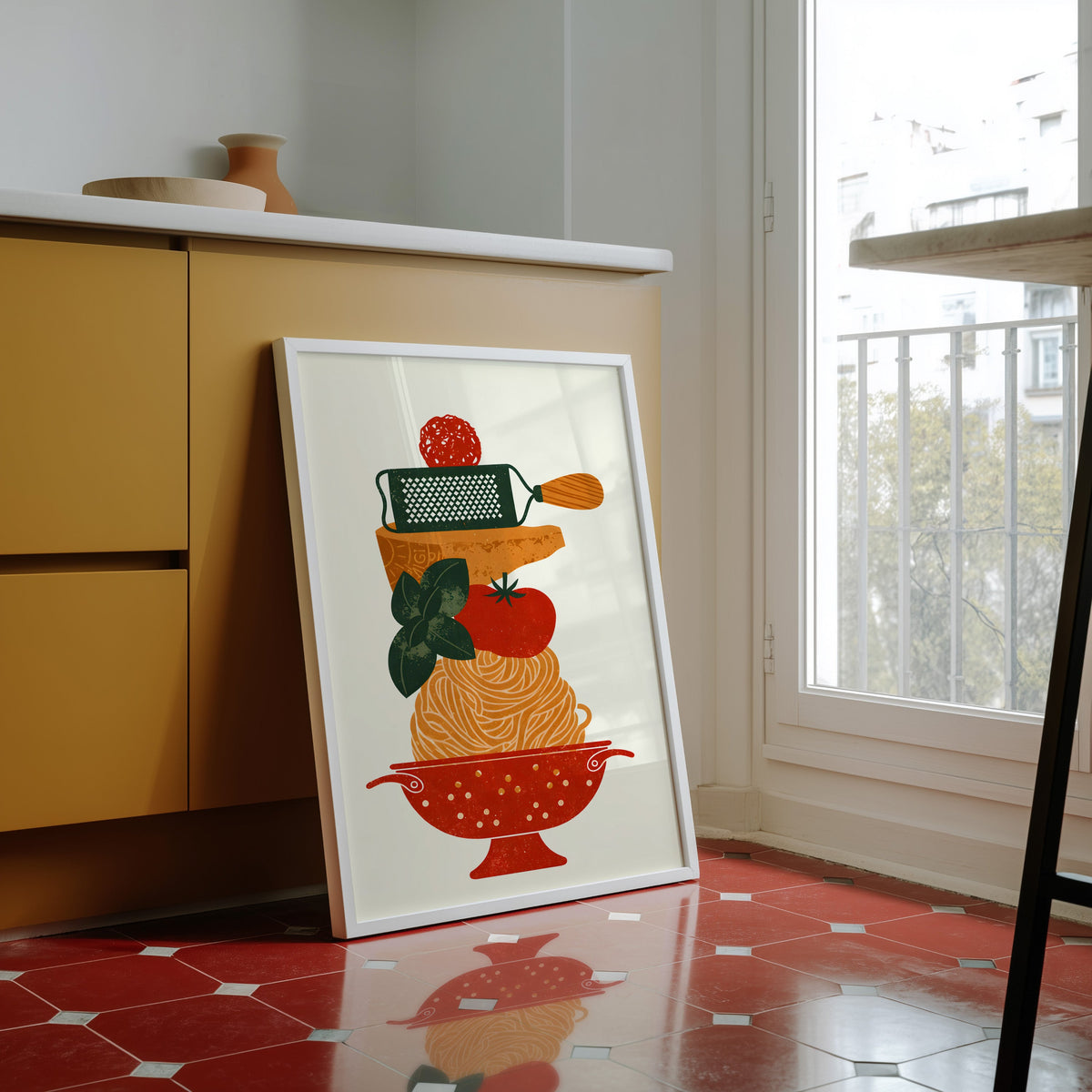 Pasta colander print in a white frame against yellow cabinets on red tiles