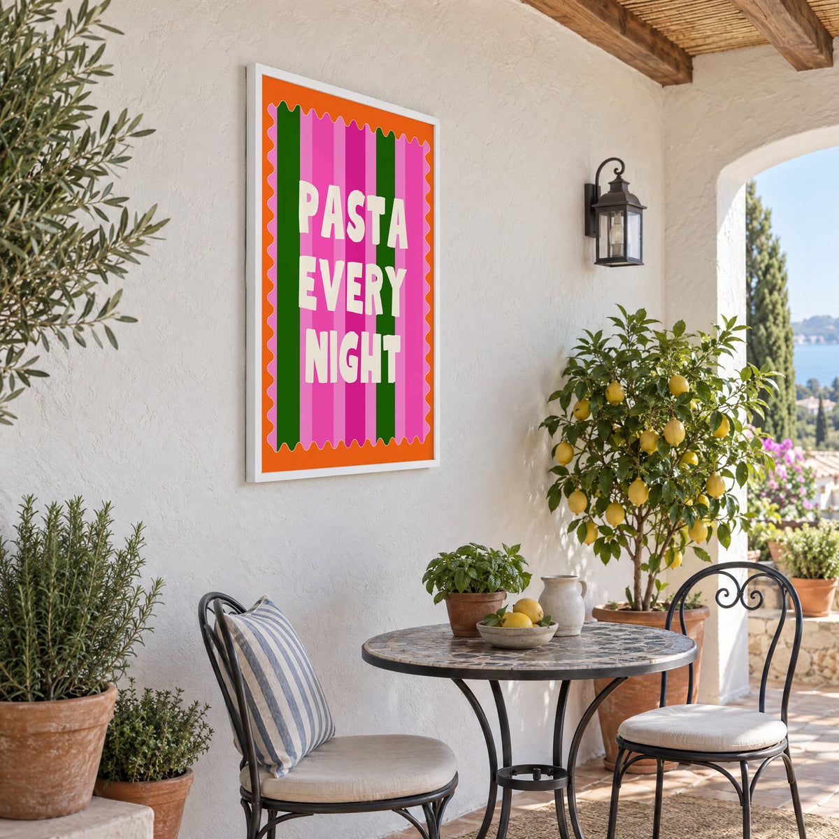 Pasta Every Night pink stripe print in a white frame on a sunny patio wall beside a potted lemon tree