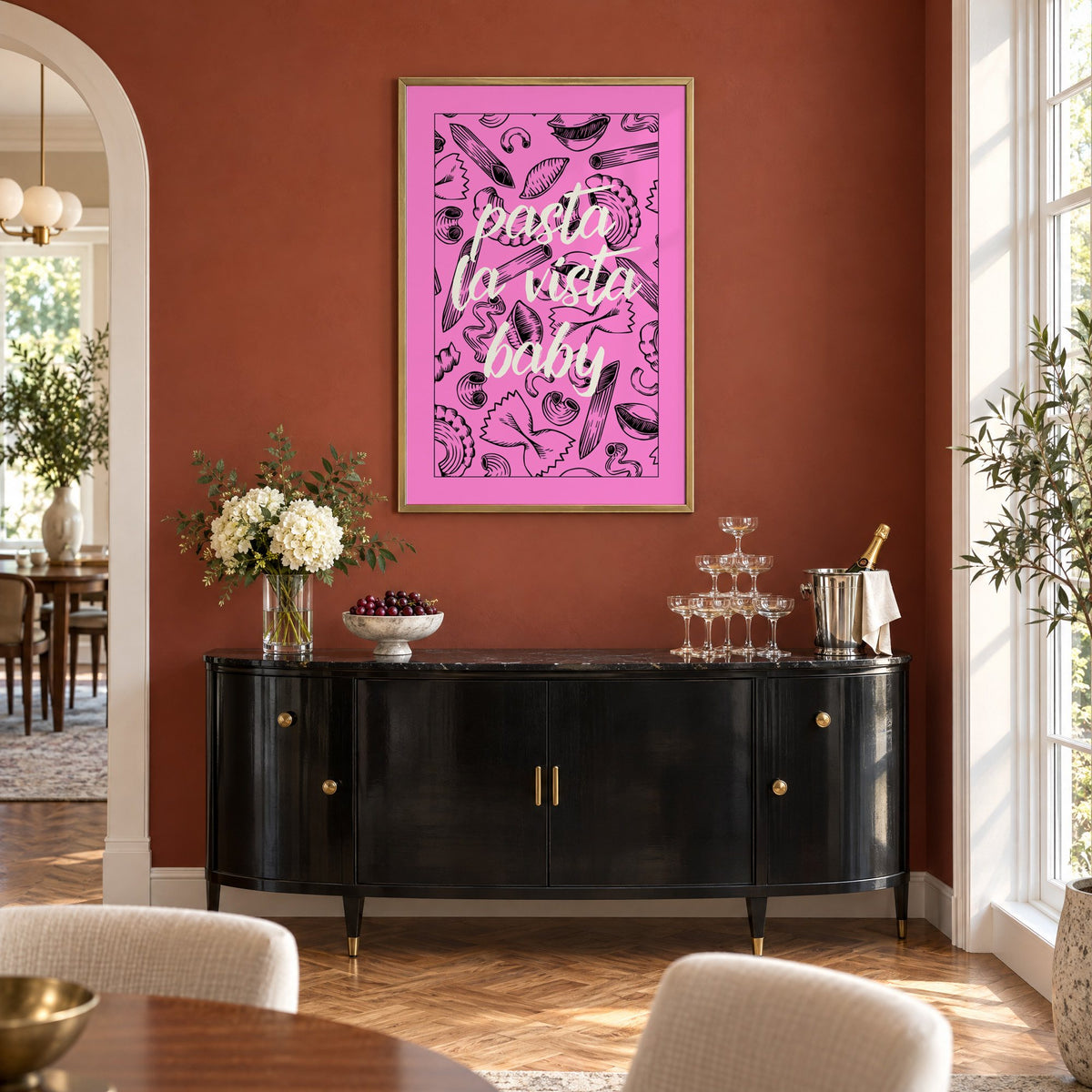 Pasta la vista baby pink print in a brass frame on a terracotta wall above a black buffet with a champagne tower