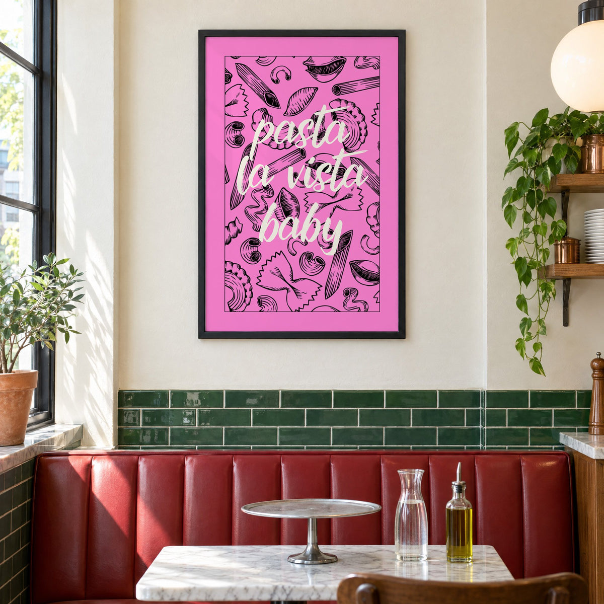 Pasta la vista baby pink print in a black frame above a red leather booth in a sunny pizzeria