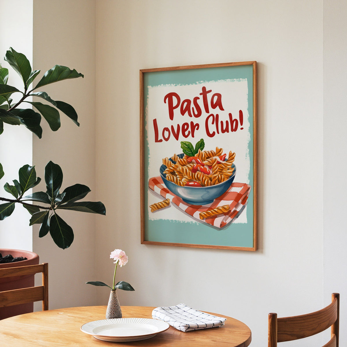 Pasta Lover Club fusilli print in a walnut frame above a round table beside a fiddle-leaf fig