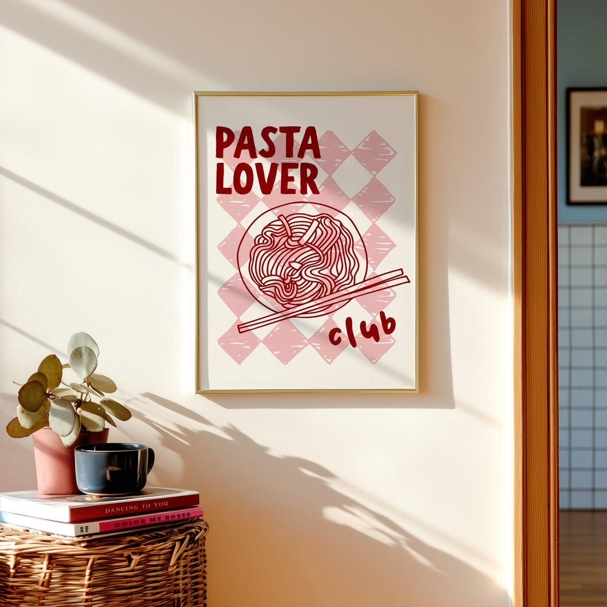 Pasta Lover Club print shown in a gold frame above a basket of books and a pilea plant