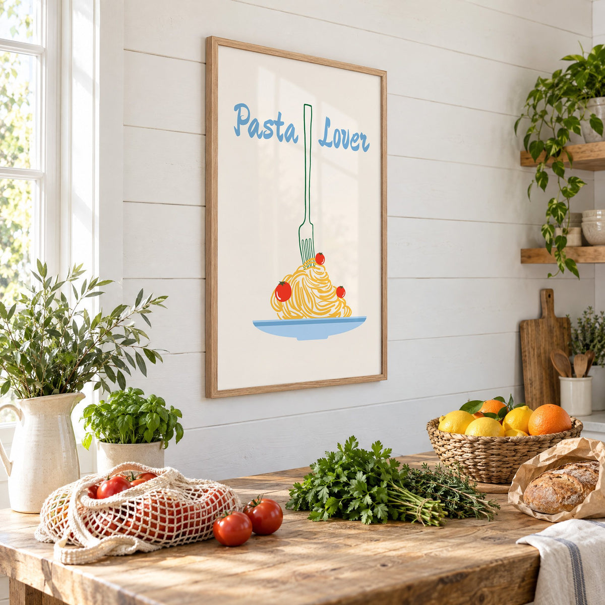 Pasta Lover fork and spaghetti print in an oak frame on a shiplap wall above a farm table with market tomatoes and citrus, seen at an angle