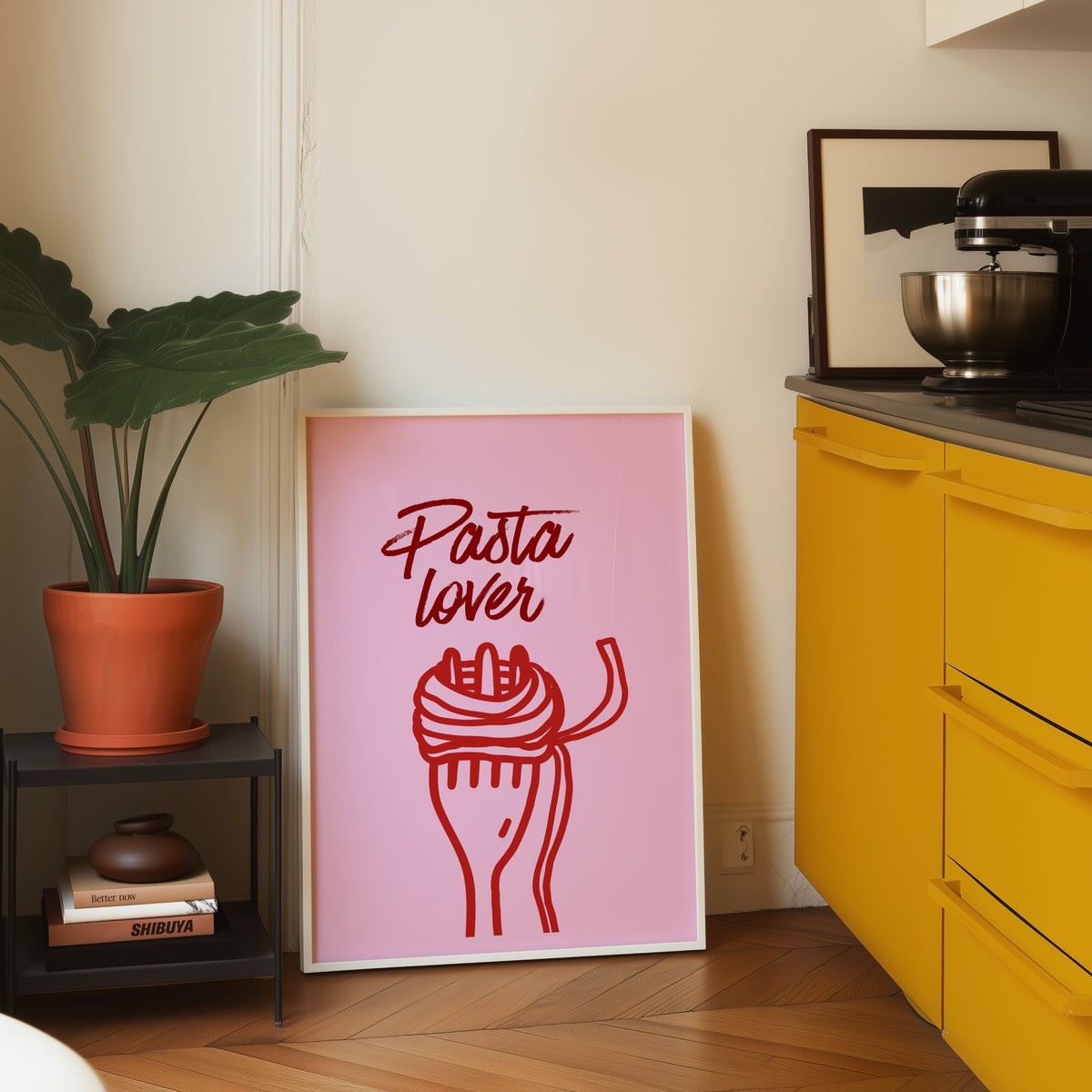Pasta Lover print in a white frame leaning on parquet beside a yellow kitchen