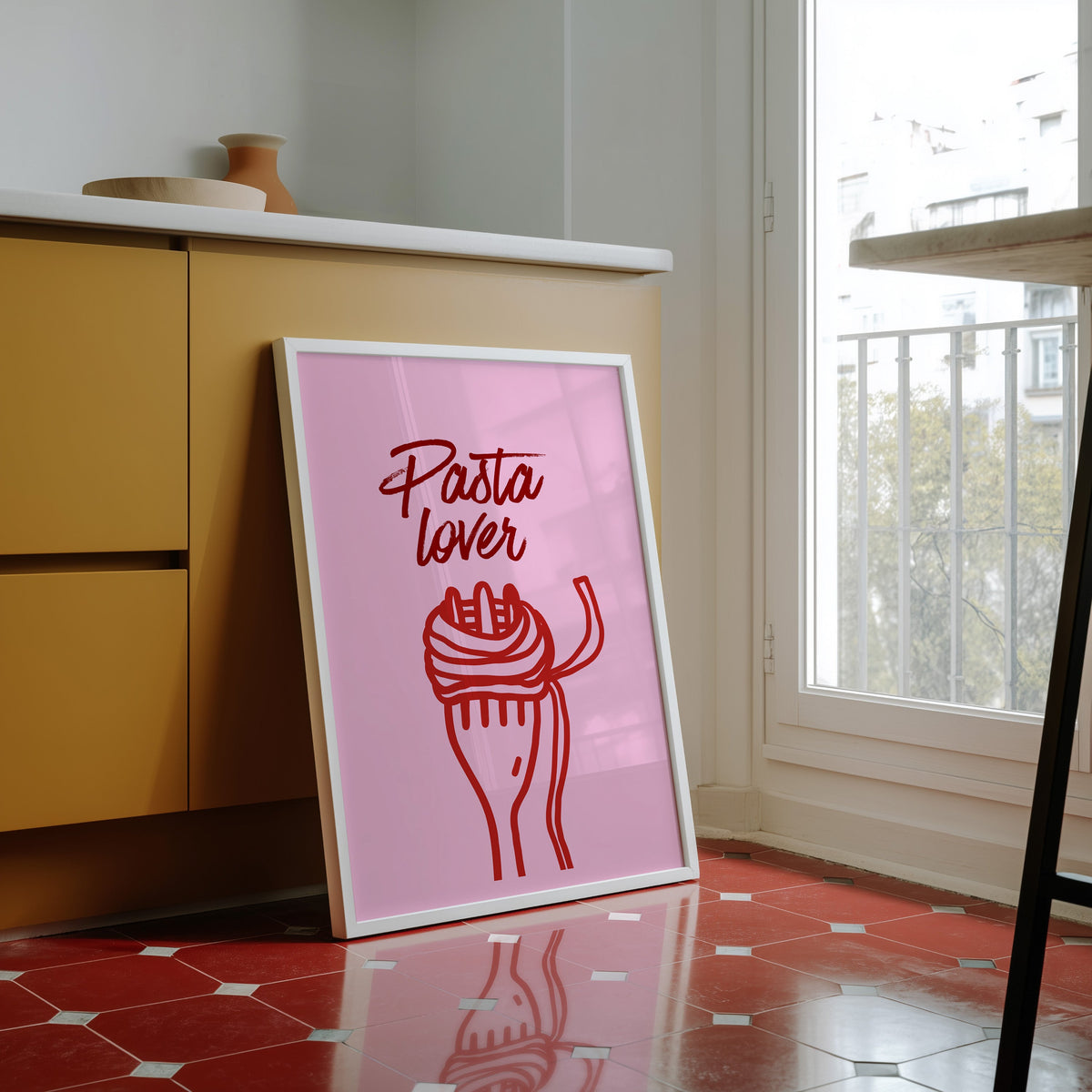 Pasta Lover print in a white frame against yellow cabinets on a red tiled floor
