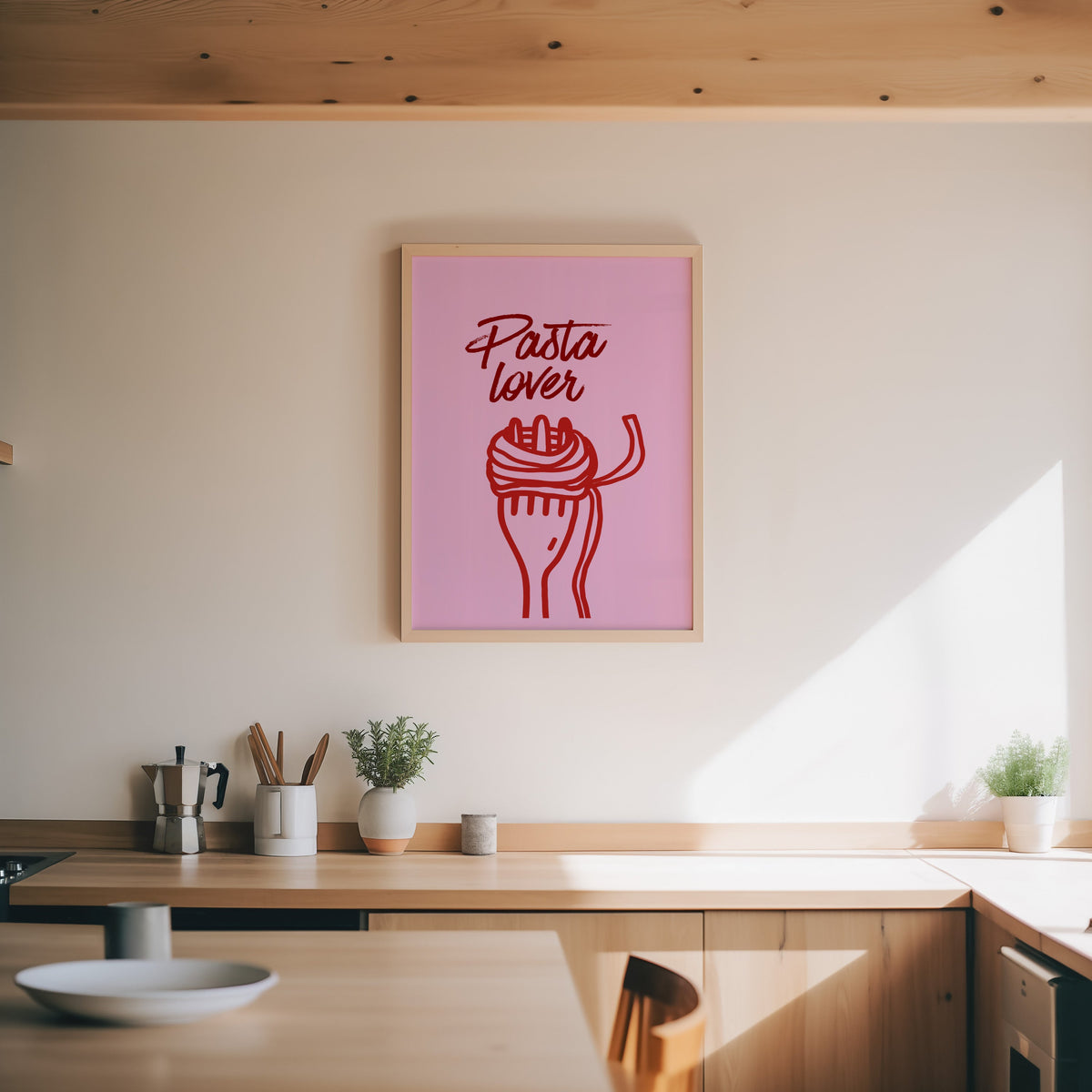 Pasta Lover print in an oak frame above a wood counter with a moka pot and herbs