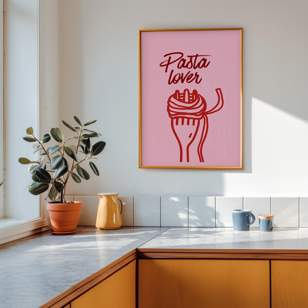 Pasta Lover print in a gold frame above a marble counter with a yellow ceramic jug