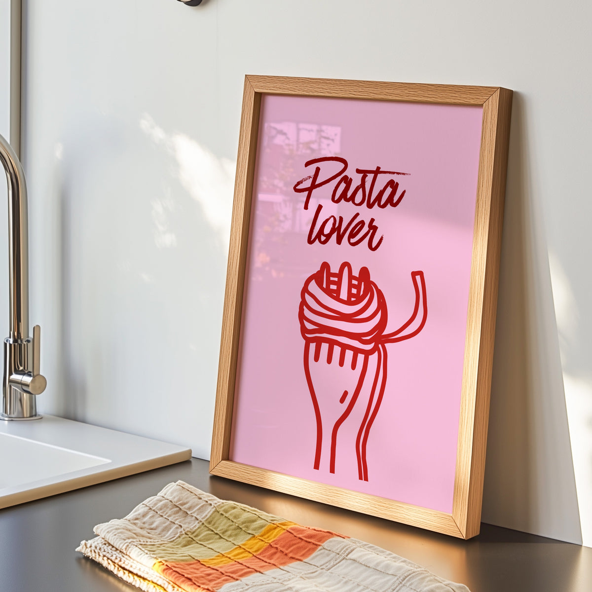 Pasta Lover print in an oak frame by the kitchen sink beside a striped tea towel