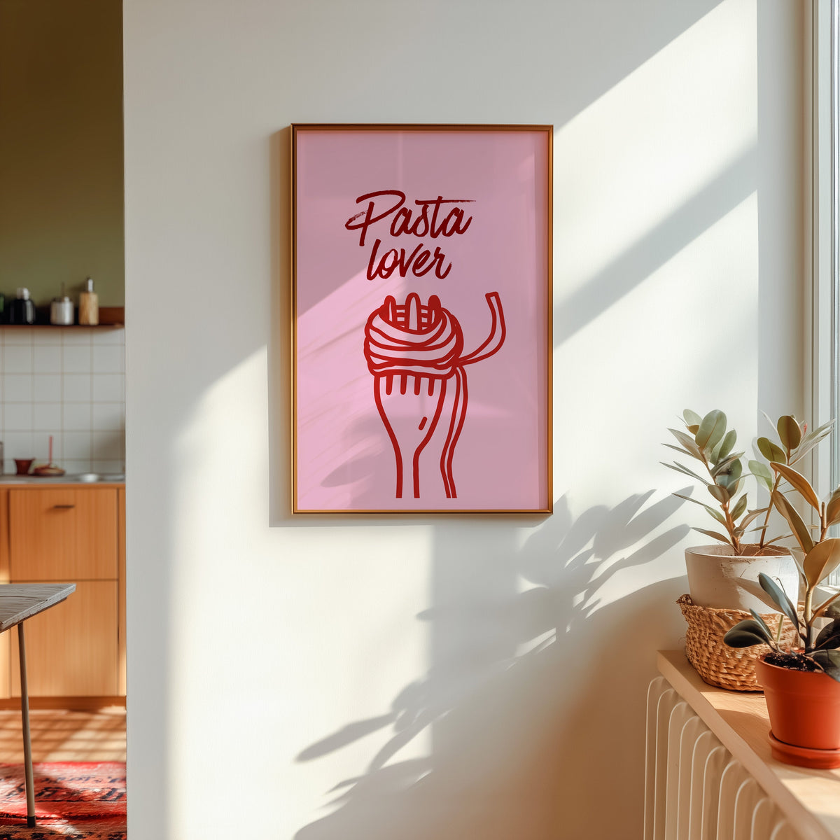 Pasta Lover print in a gold frame in sunlight with plants and a kitchen beyond