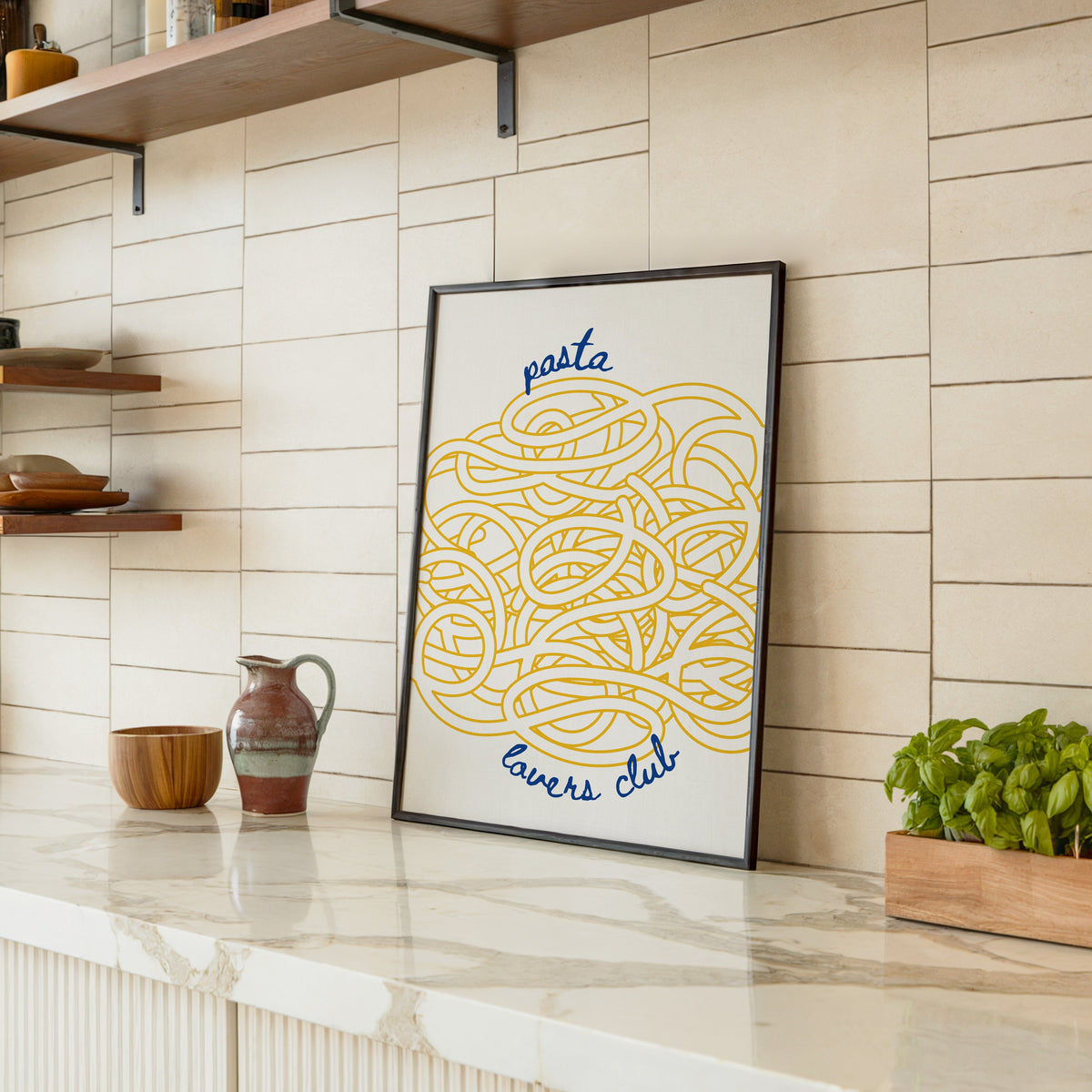 Pasta Lovers Club print in a black frame leaning on a marble counter in a tiled kitchen