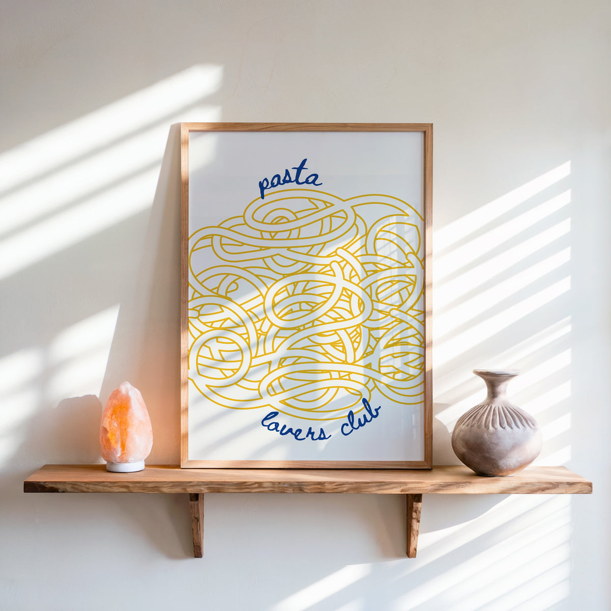 Pasta Lovers Club print in an oak frame on a live-edge shelf beside a salt lamp