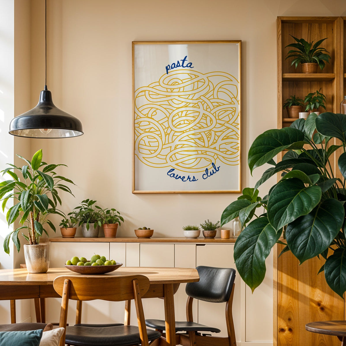 Pasta Lovers Club print in an oak frame in a dining room above a plant-lined sideboard
