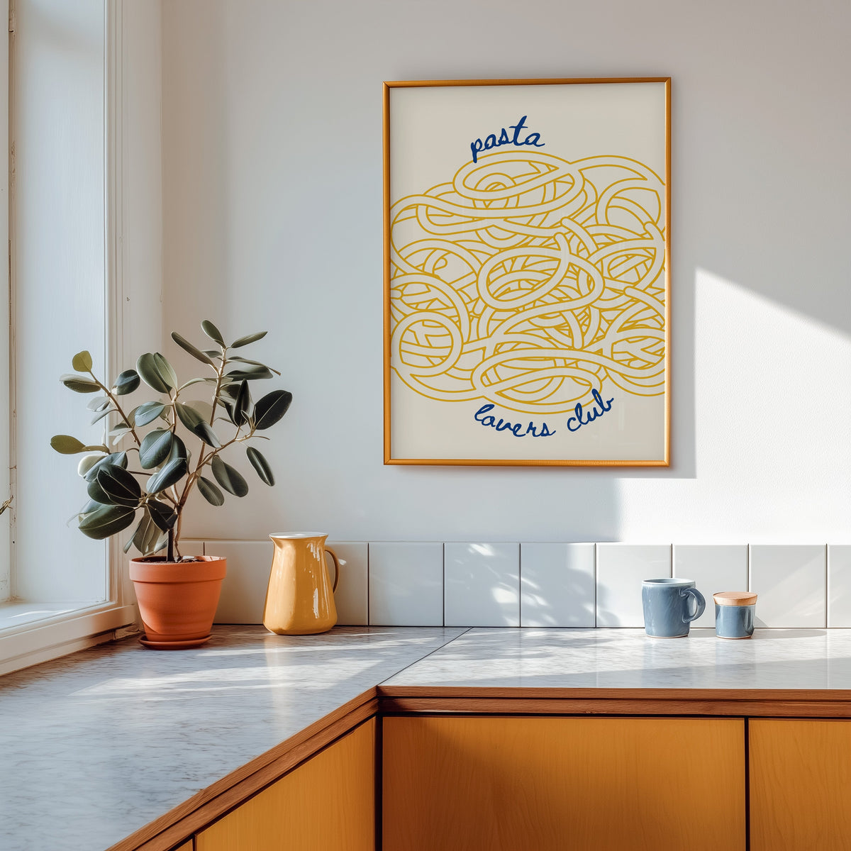 Pasta Lovers Club print shown in a gold frame above a marble counter in a tan kitchen