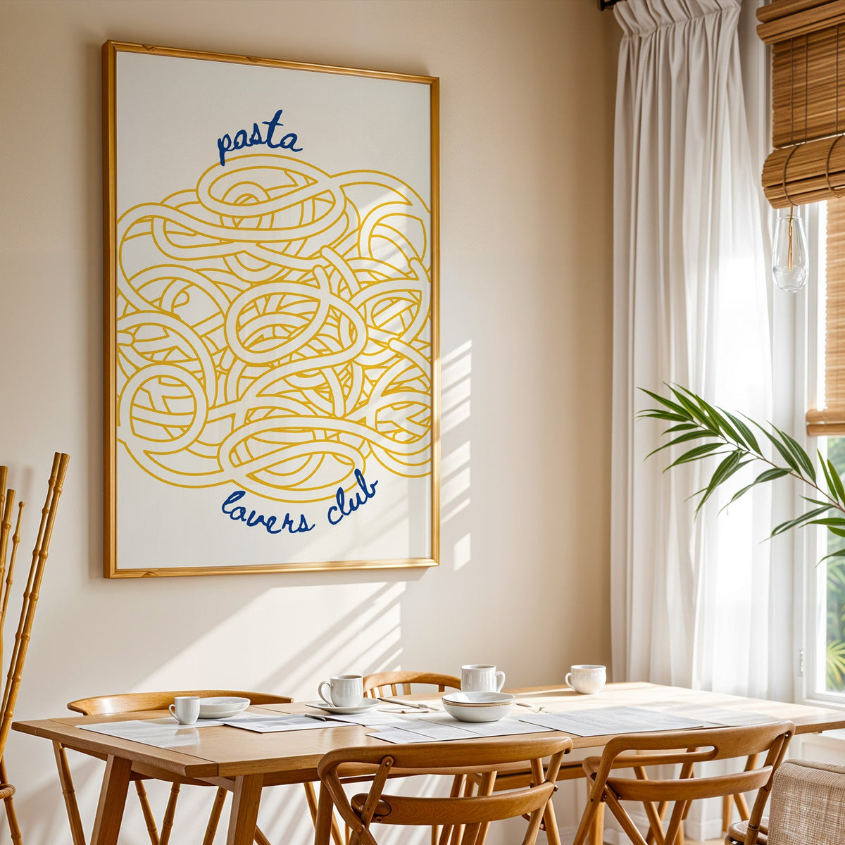 Pasta Lovers Club print shown in a gold frame above a breakfast table by a curtained window