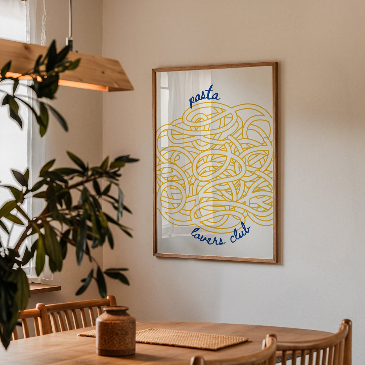 Pasta Lovers Club print in a walnut frame above a dining table with olive branches