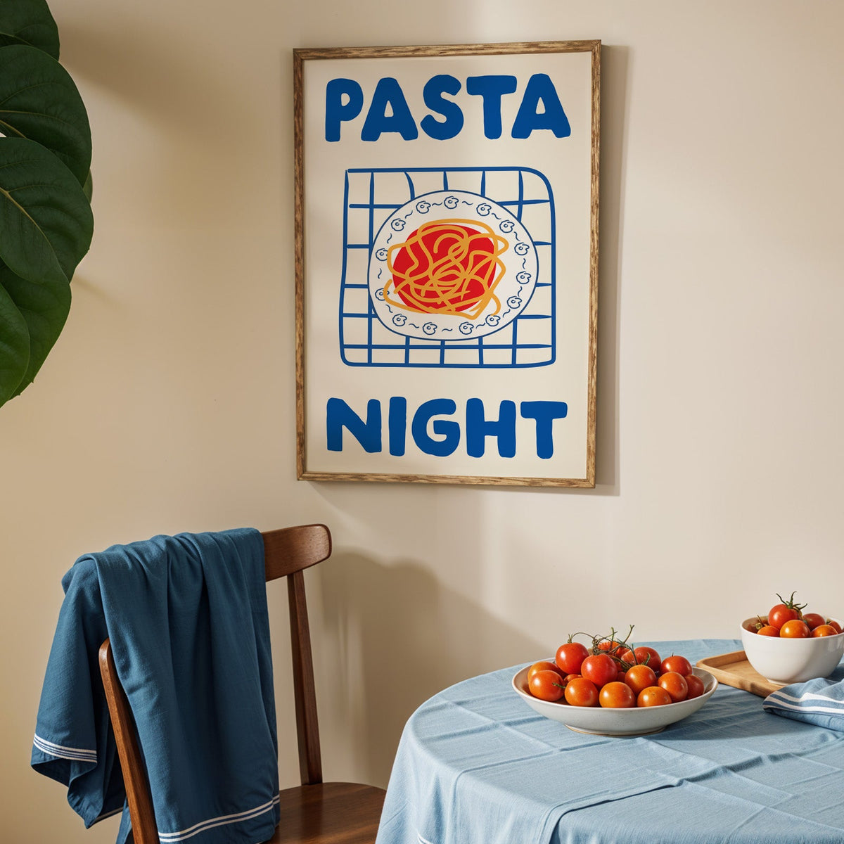 Pasta night blue print in an oak frame above a blue linen table with ripe tomatoes
