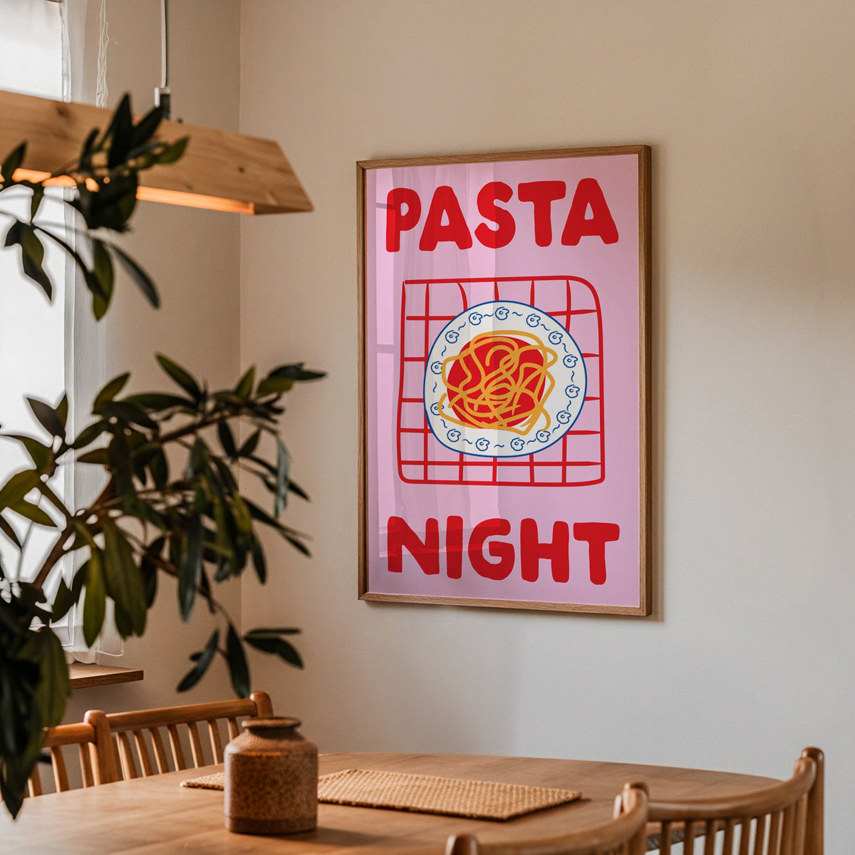 Pasta night pink print in a walnut frame above a dining table beside an olive tree